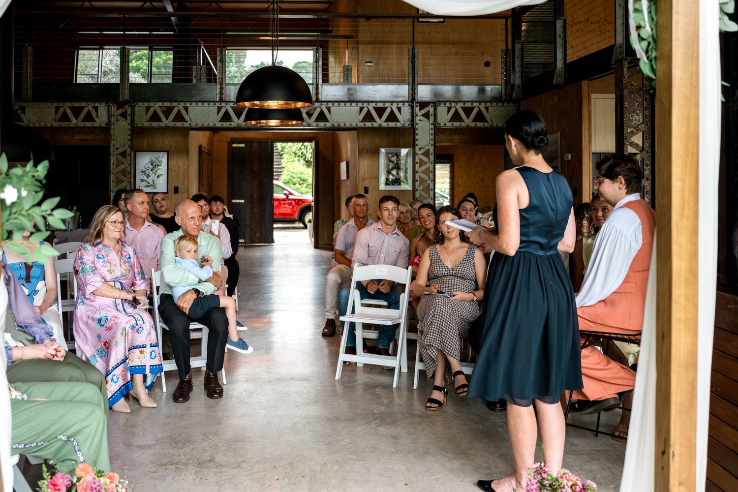 Wedding guests seated in rows at an open-air rustic venue during a daytime ceremony.