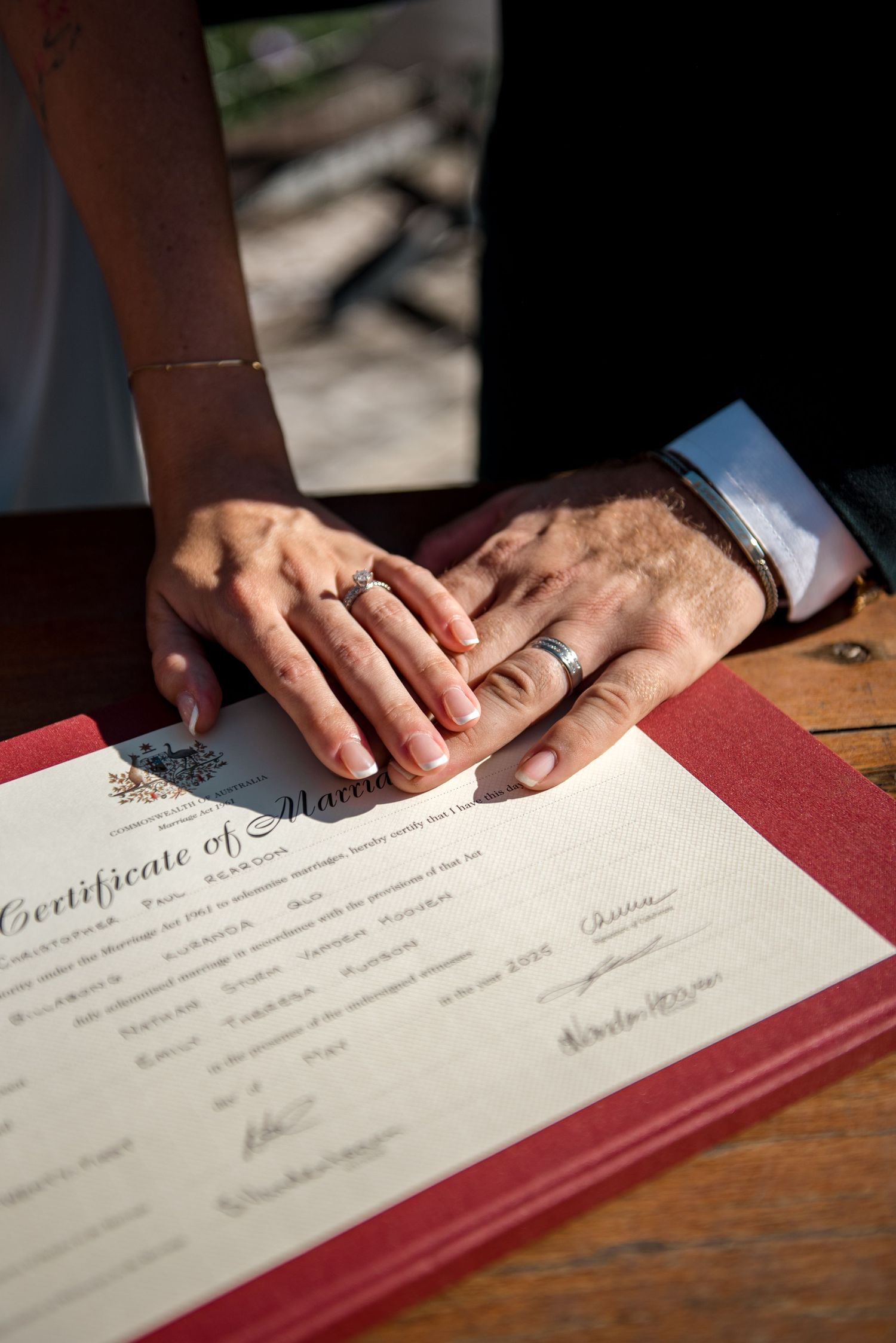 Newlyweds placing hands on marriage certificate after signing.
