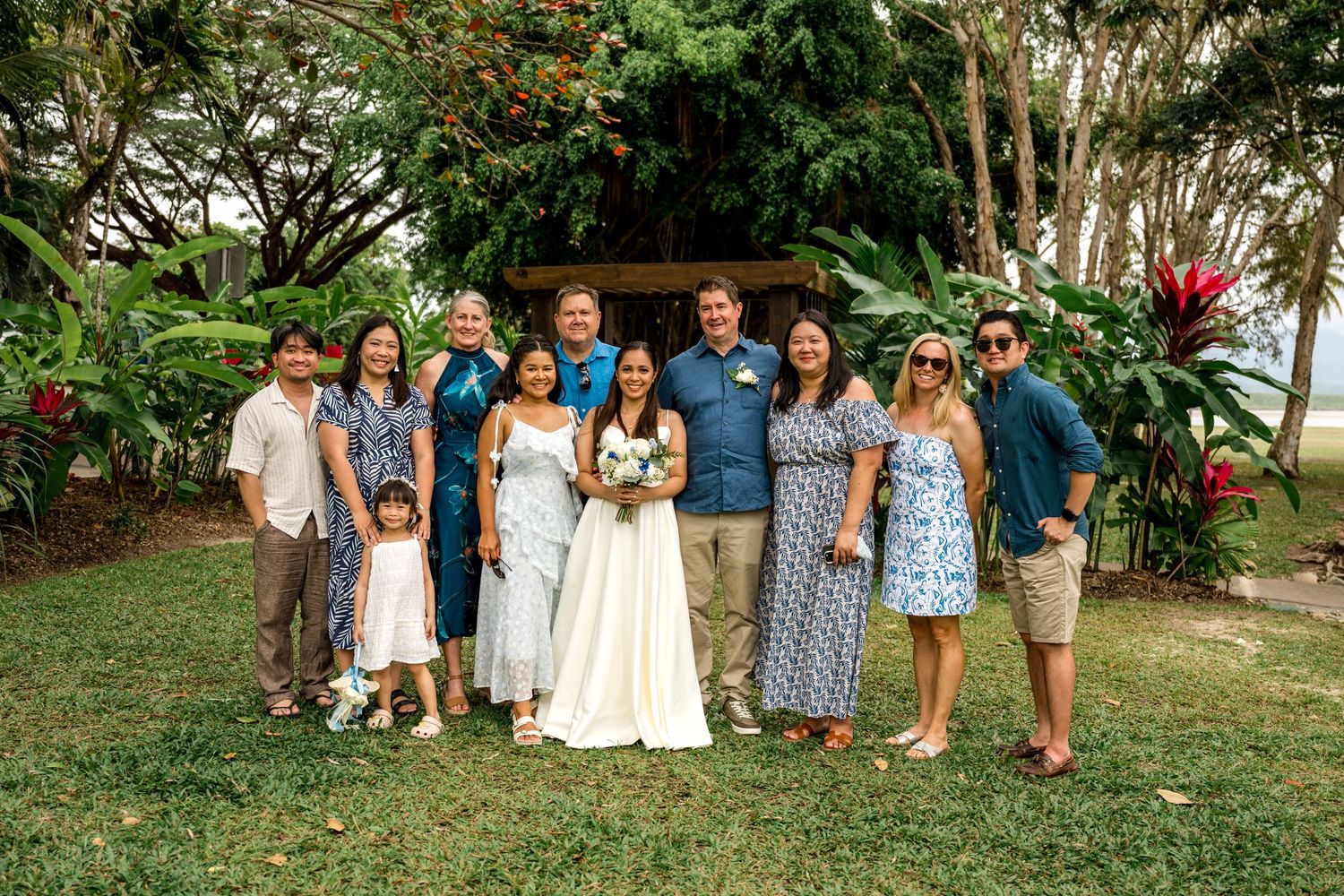 Bride and groom celebrate with large family group in lush tropical garden after wedding at Little Cove, Port Douglas.