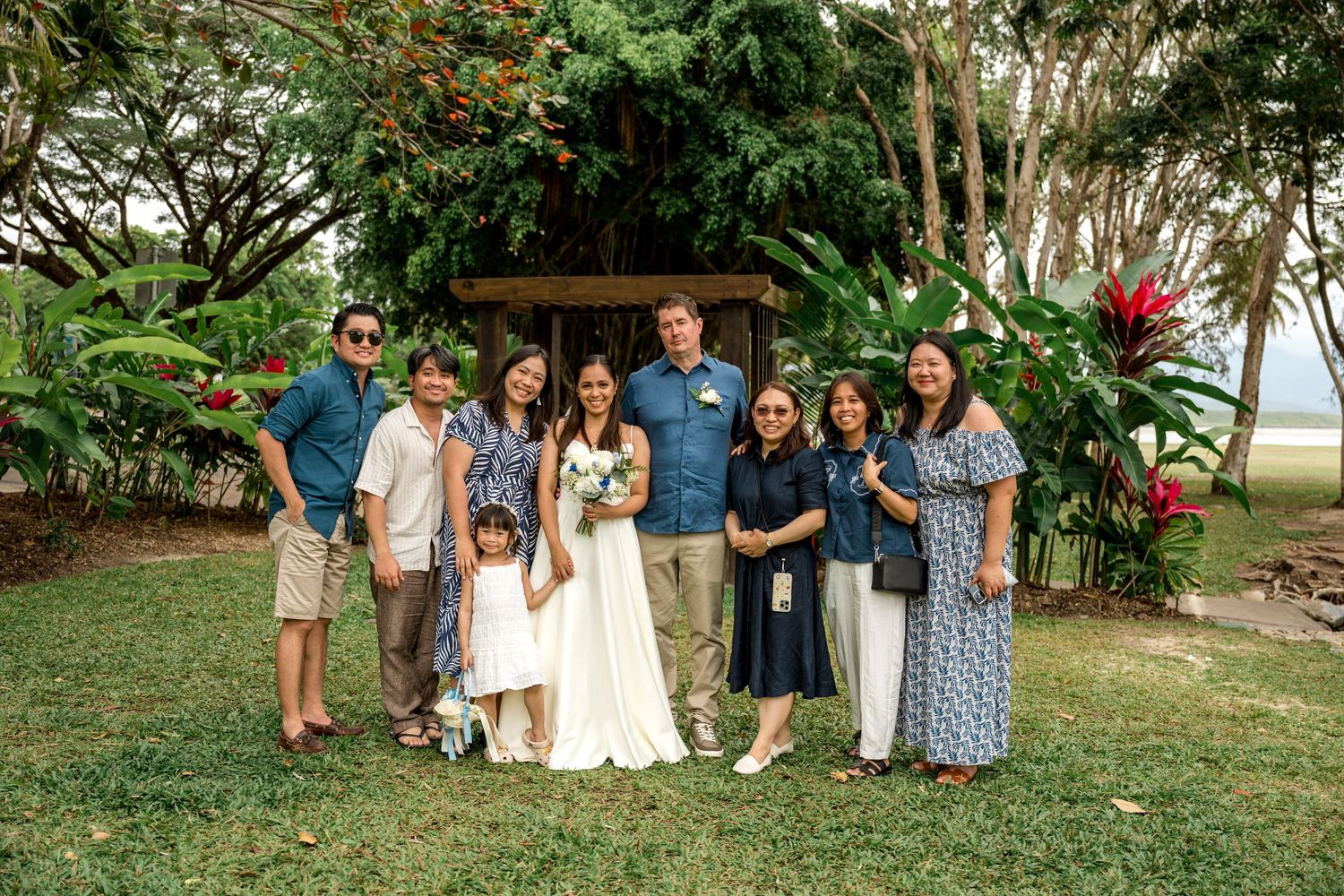 Bride and groom celebrate with family group photo surrounded by vibrant tropical greenery at Little Cove, Port Douglas.