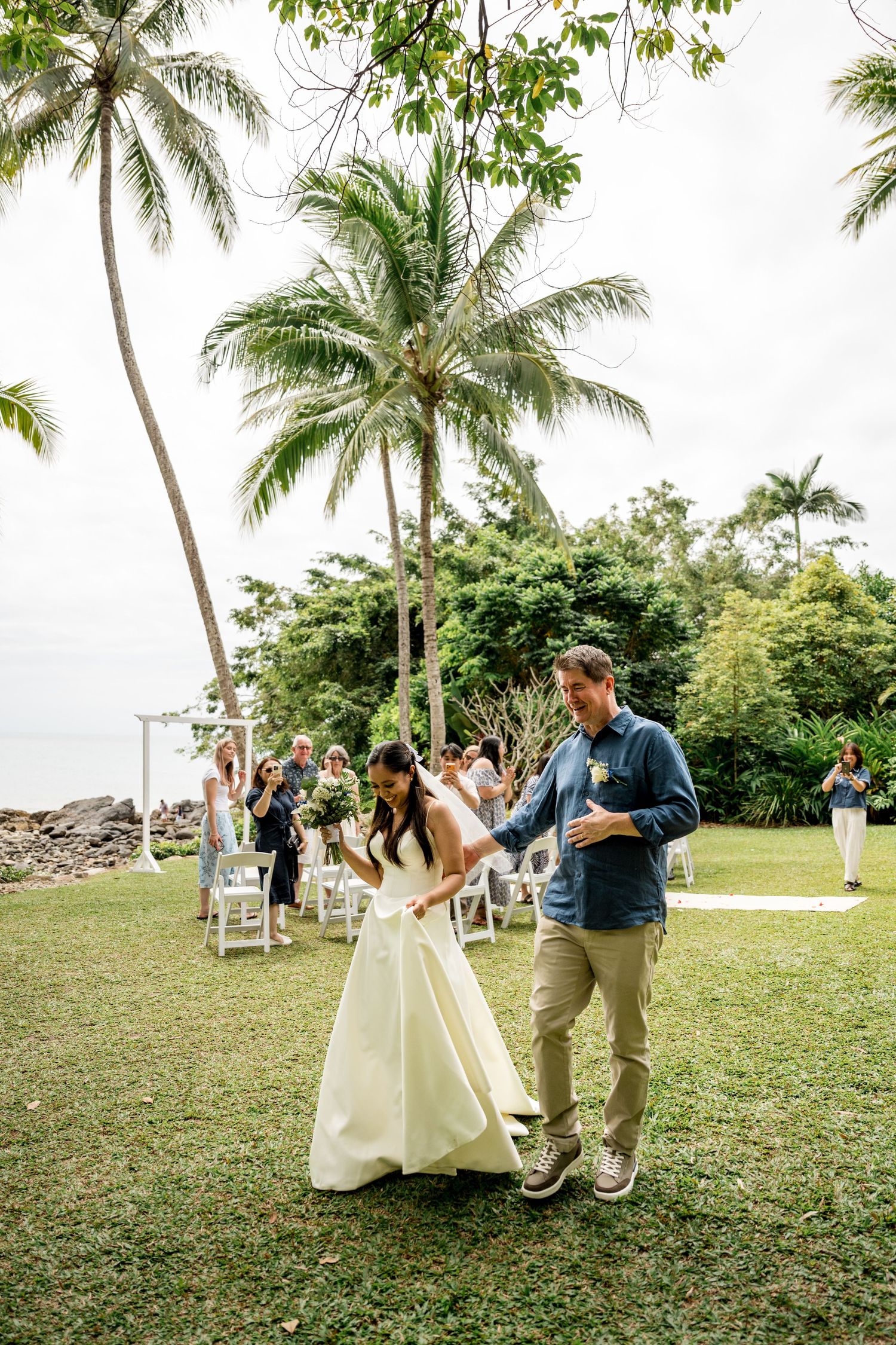 Newlyweds walking back down the aisle at a tropical outdoor wedding with palm trees at Little Cove, Port Douglas.