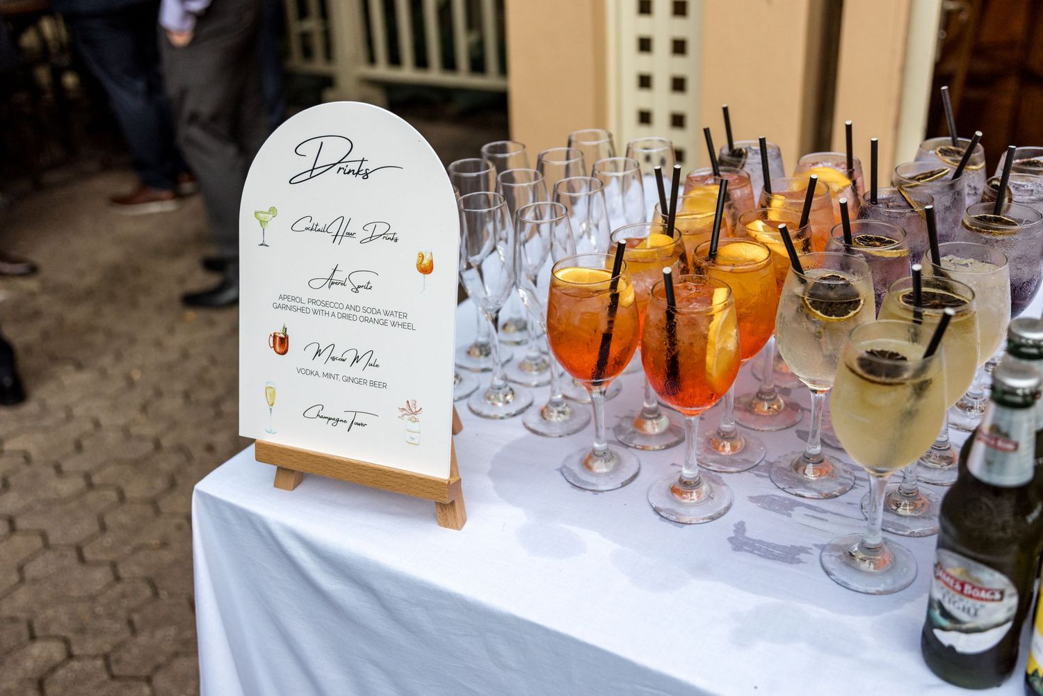 Elegant wedding cocktail hour drinks table with Aperol Spritz and champagne flutes display.