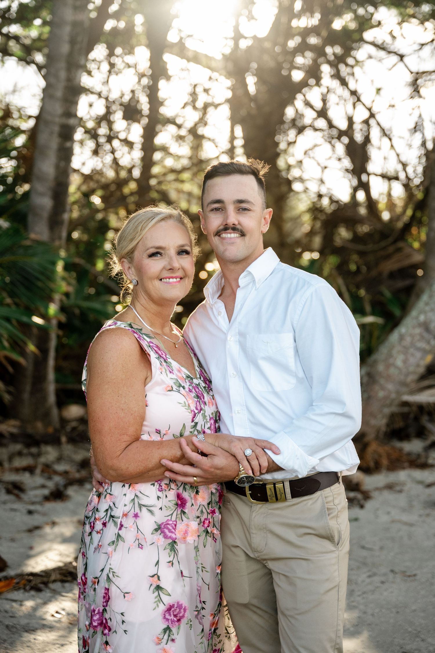 Mother and son smiling together in matching floral and white outfits at beach wedding at Four Mile Beach, Port Douglas.