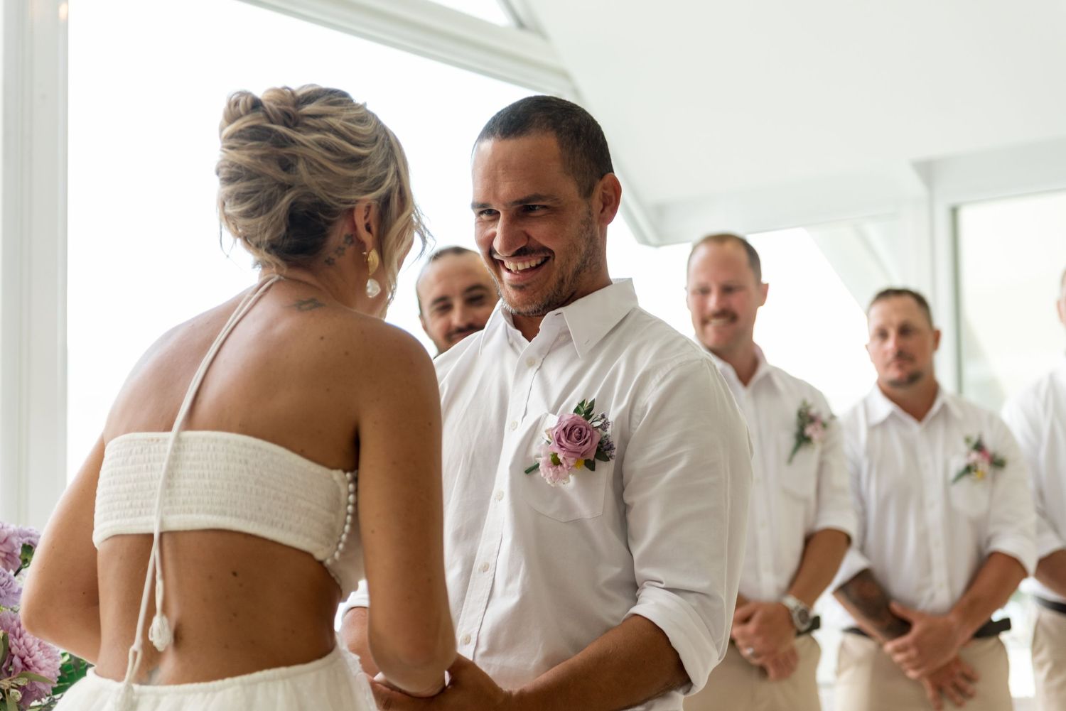 Groom smiling joyfully as he faces his bride at the wedding altar.