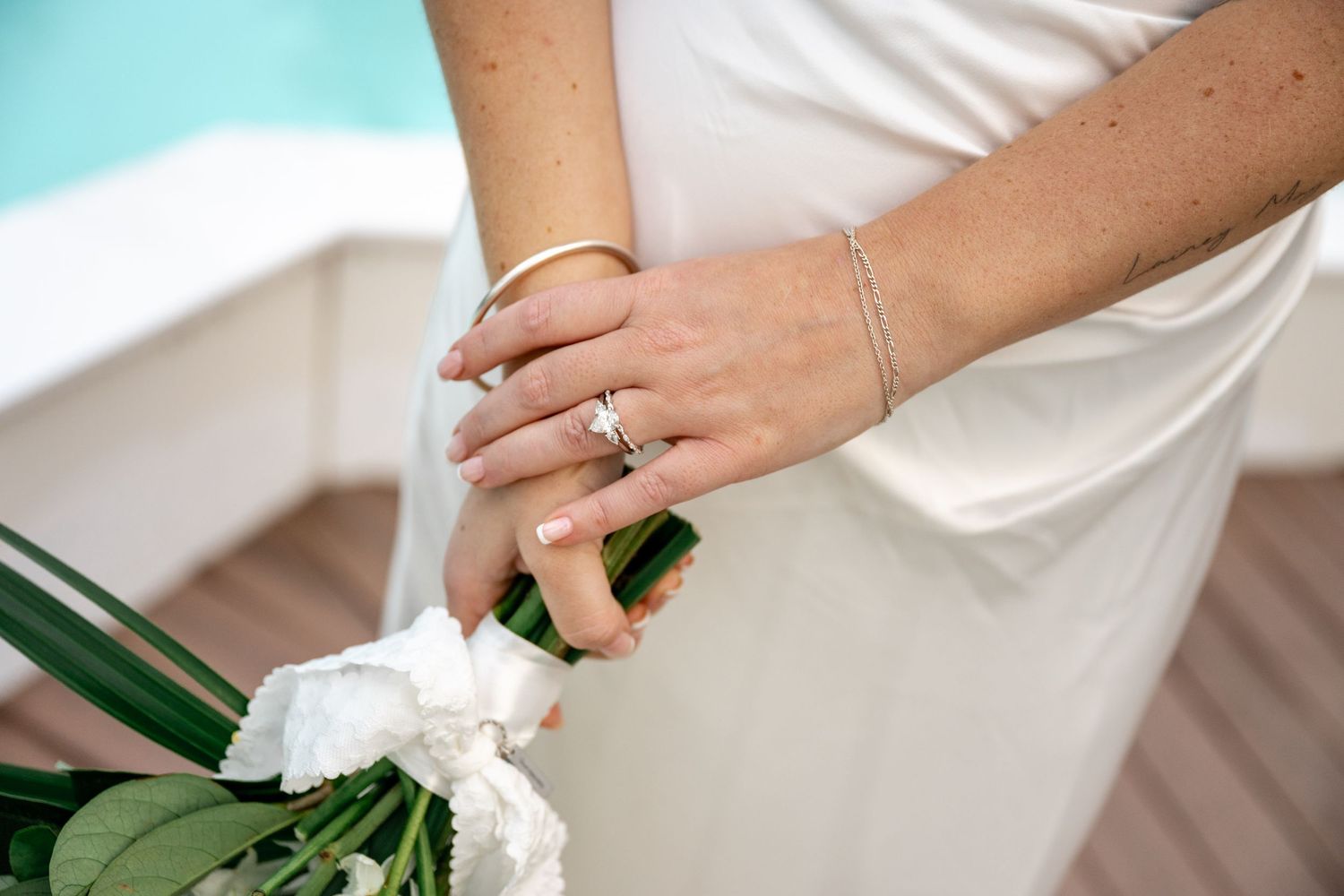 Close-up of bride's hands holding a white bouquet, showcasing her diamond ring and gold bracelet at Sheraton Grand Mirage Port Douglas.