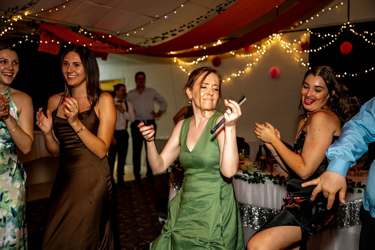 Women in colorful dresses dancing and celebrating at a wedding reception.