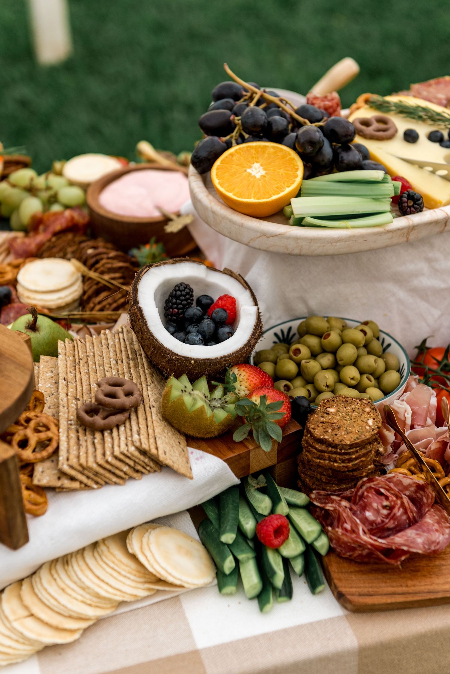 Elaborate grazing board with fruits, olives, crackers, meats, and a coconut bowl of berries.