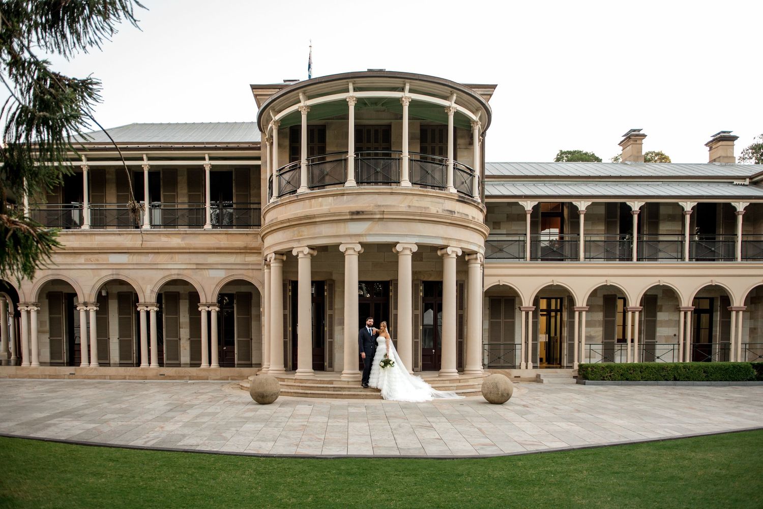 Bride and groom embracing in courtyard of grand historic colonial wedding venue.