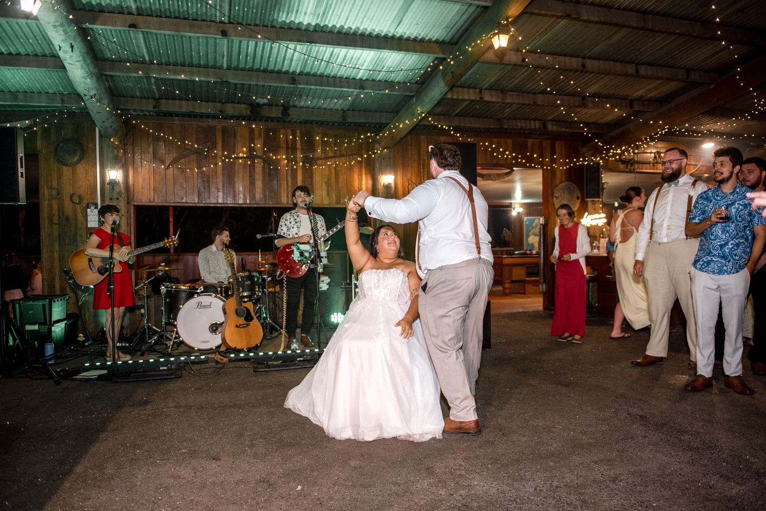 Bride and groom share first dance at rustic barn wedding with live band performing.