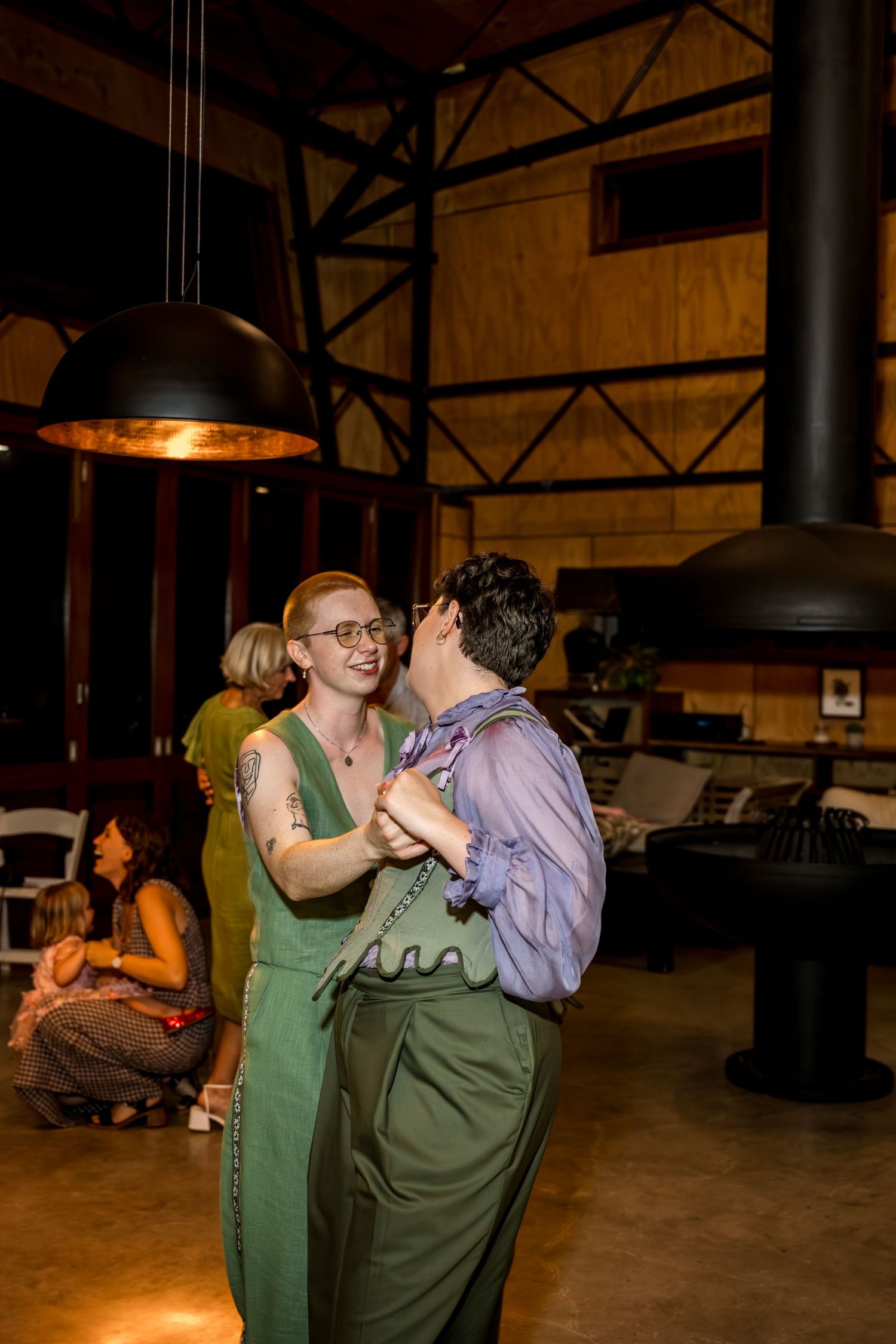 Couple in green wedding attire share a joyful first dance at their reception.