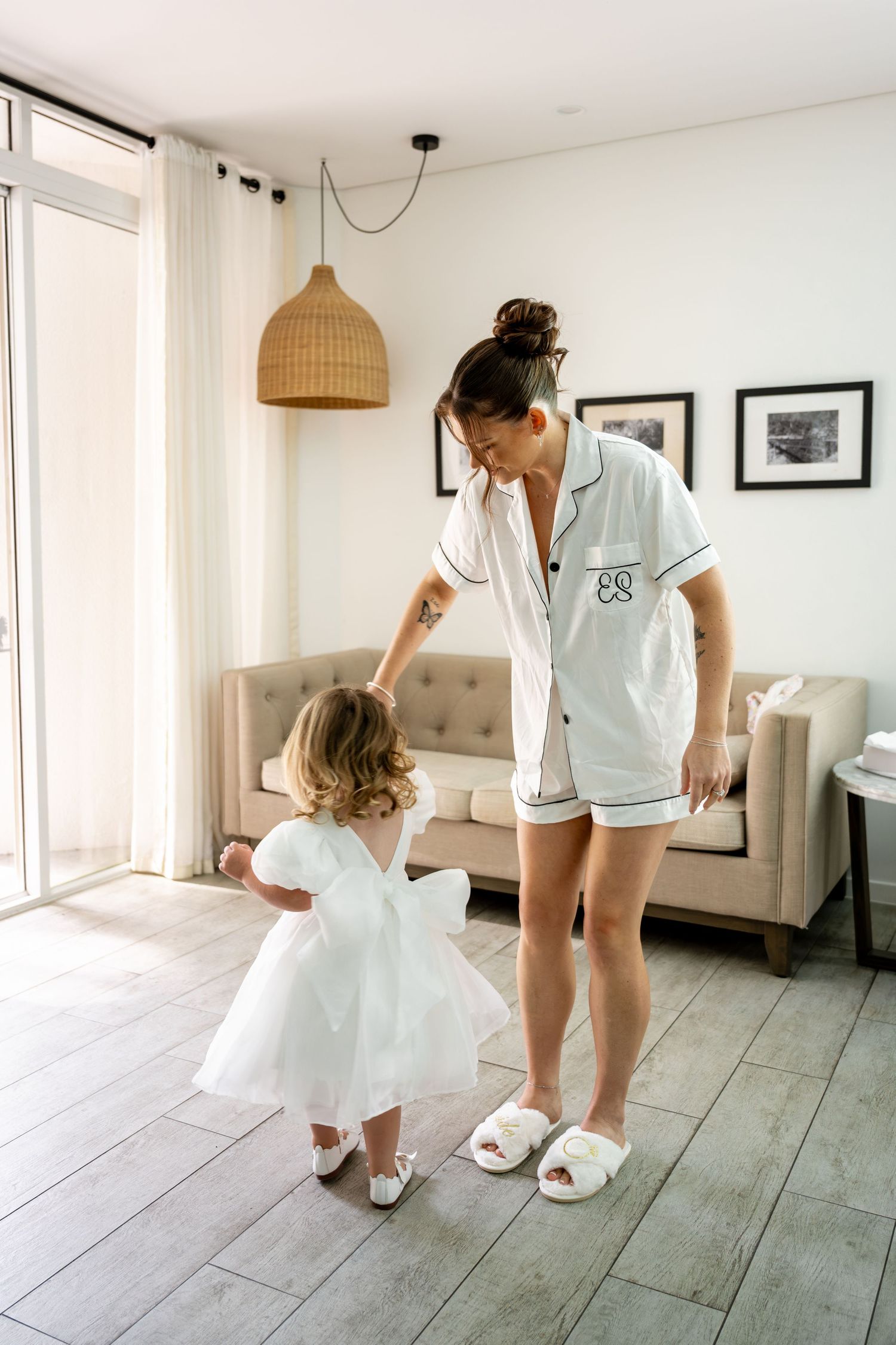 Woman in monogrammed pajamas dancing with an adorable toddler flower girl in a white dress.