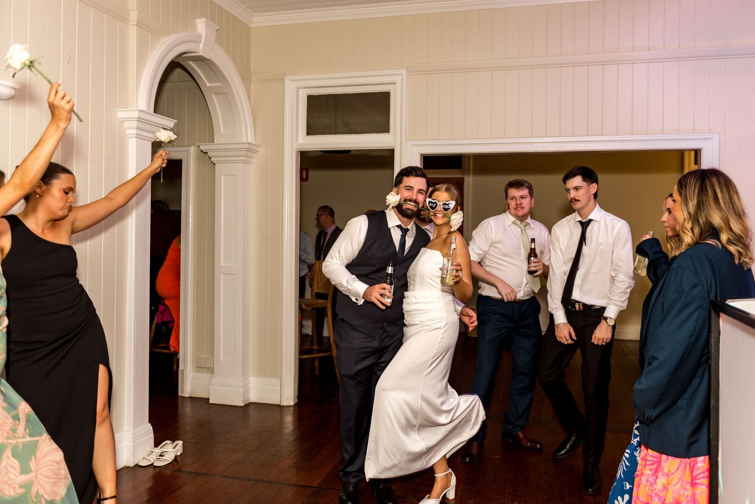 Bride and groom dancing together surrounded by wedding guests at their reception.