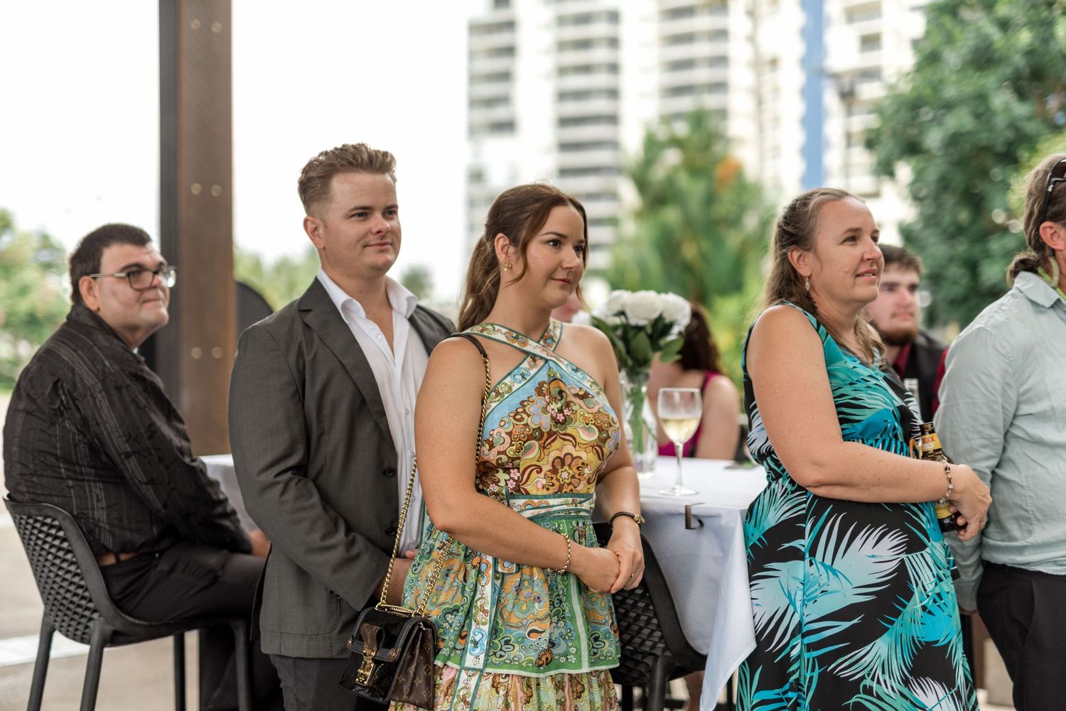 Smiling wedding guests in colorful attire enjoying the celebration at an outdoor reception.