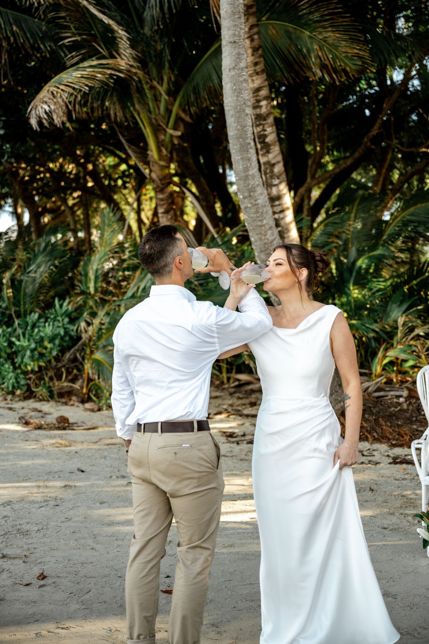 Bride and groom toasting with champagne glasses during tropical beach wedding at Four Mile Beach, Port Douglas.