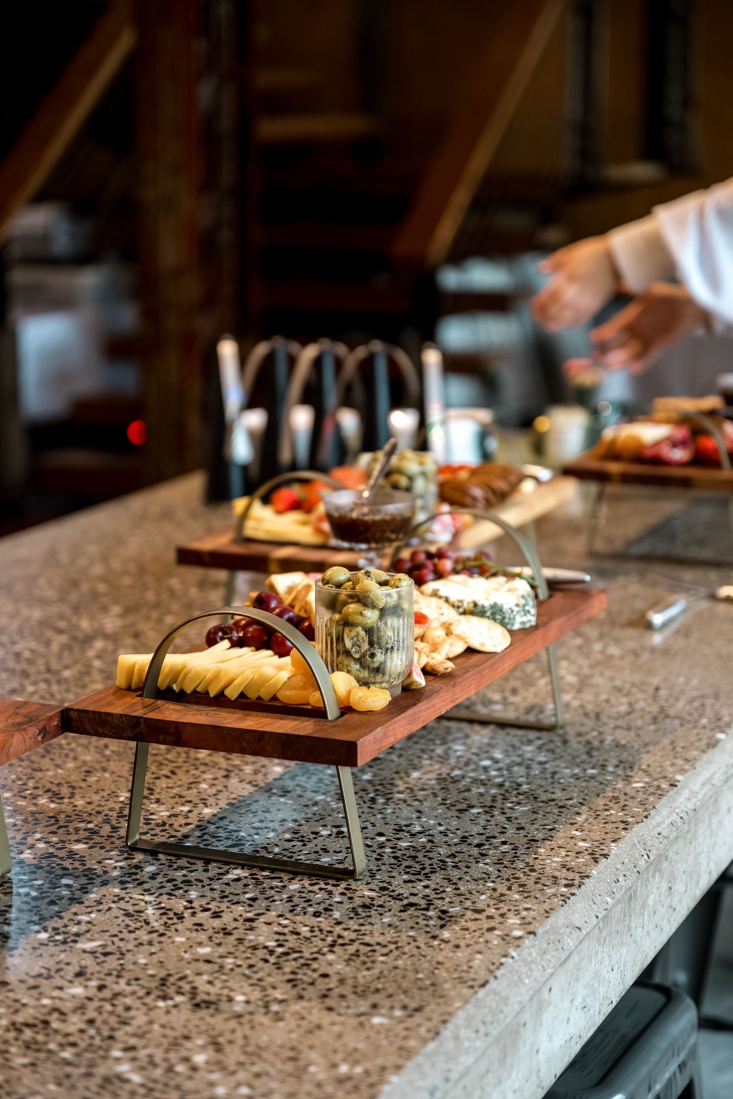 Elegant charcuterie boards with cheese, fruit, and crackers displayed on wooden serving stands.