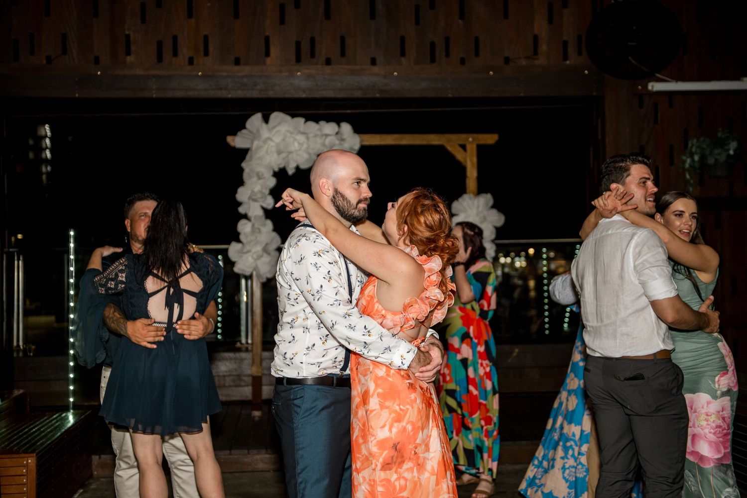 Wedding guests share romantic slow dances together on the dance floor at a night reception.