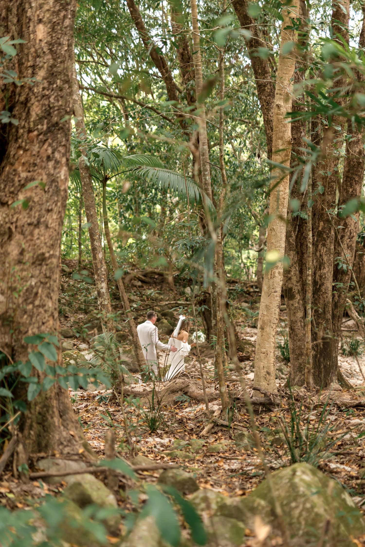 Bride and groom sharing a moment together deep in a lush green forest setting.