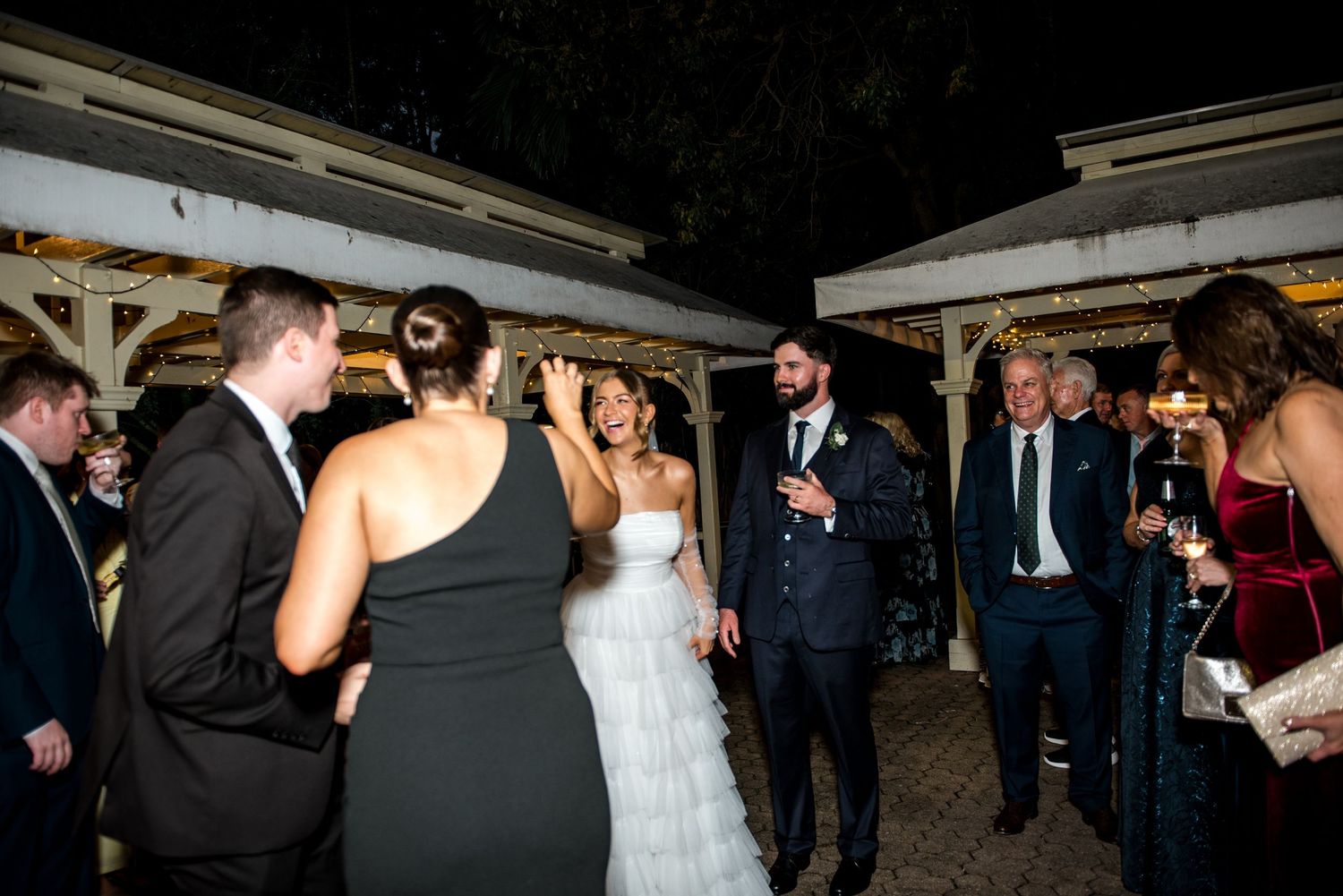 Bride and groom mingle with guests at an elegant outdoor evening wedding reception.