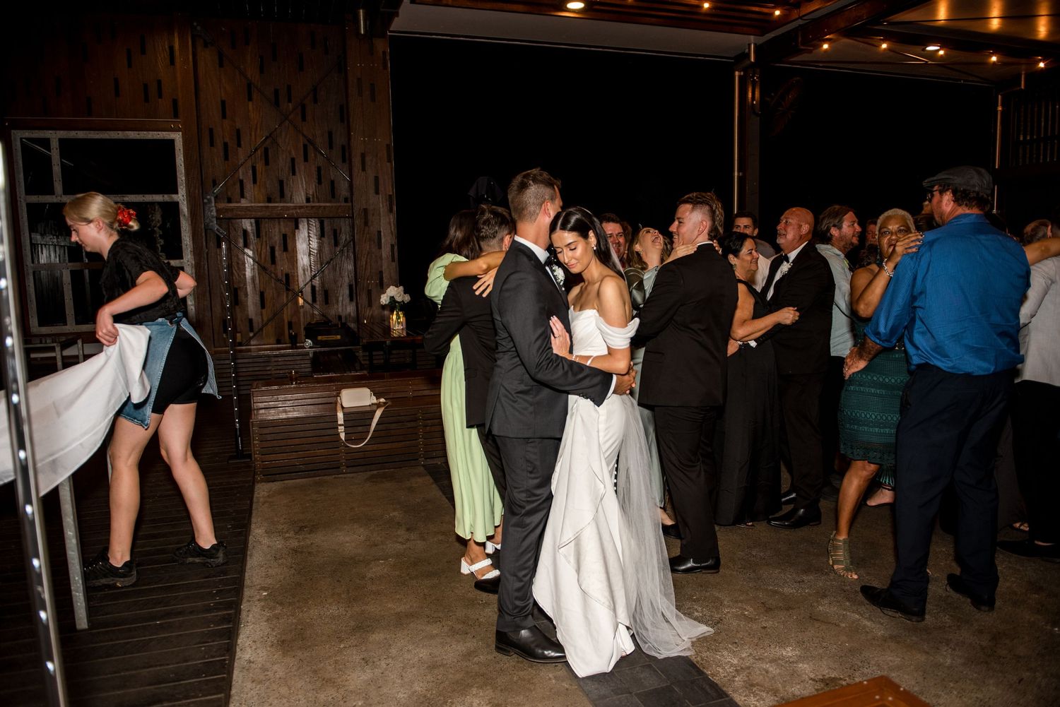 Bride and groom share a romantic dance surrounded by celebrating guests at their wedding reception.