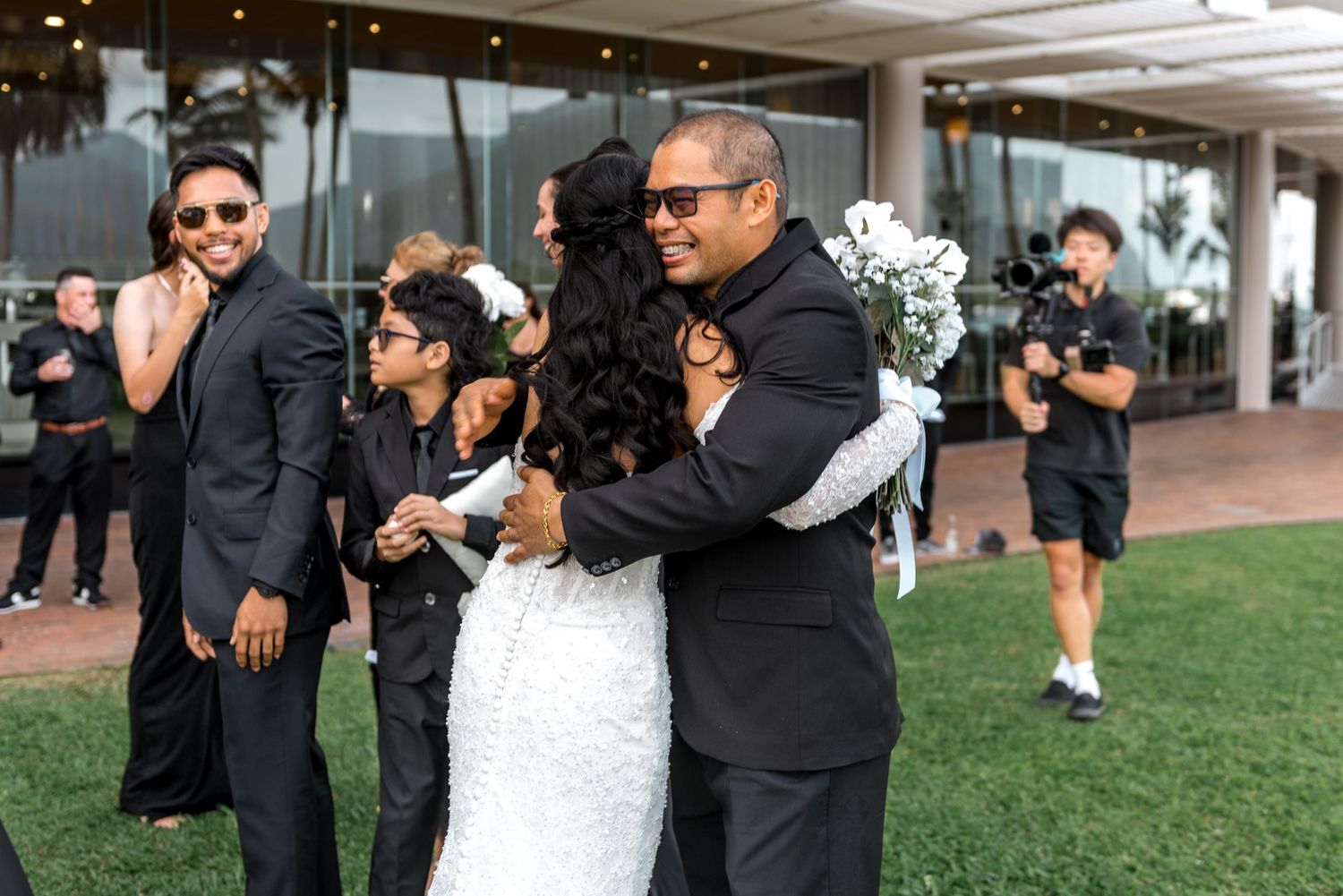 Emotional bride embraces family member in heartfelt congratulations after outdoor beach wedding ceremony.