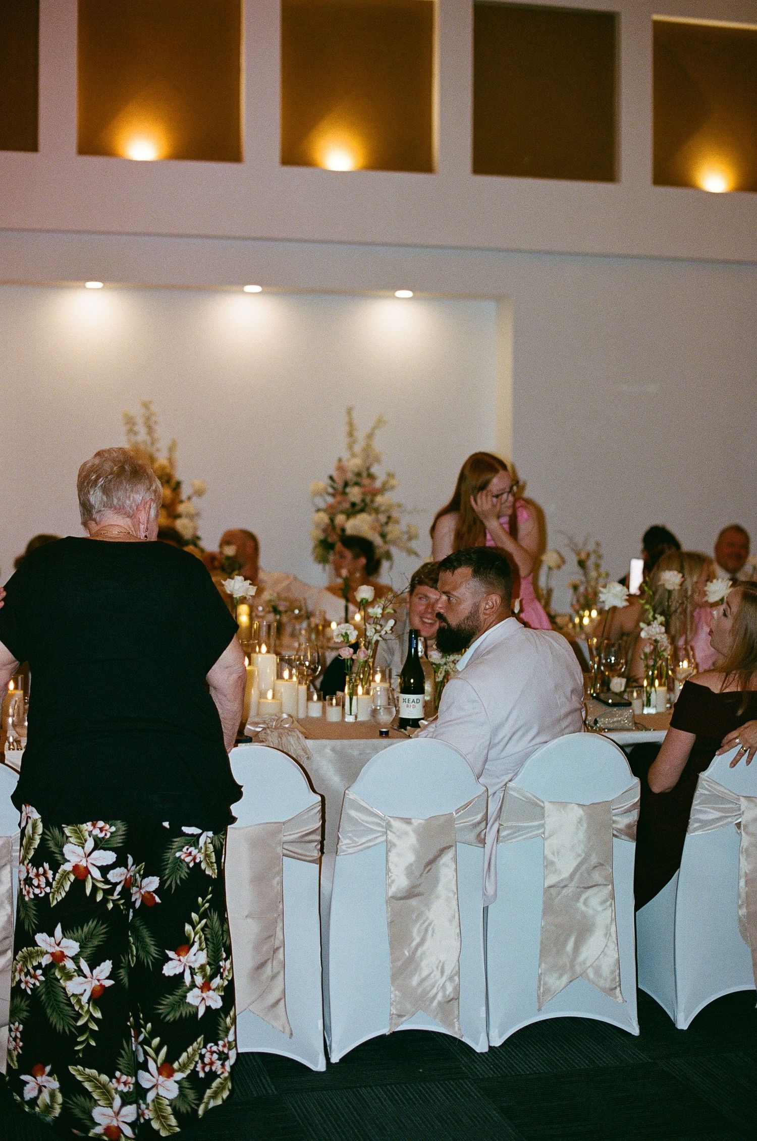 Wedding guests socializing at an elegantly lit reception dinner table.