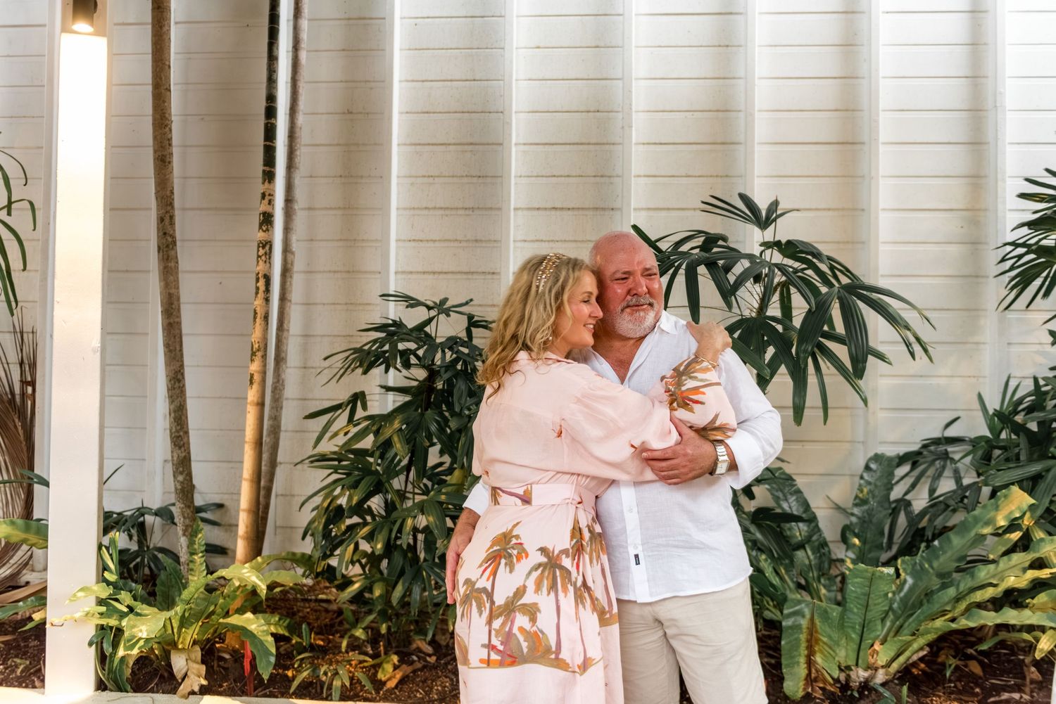 Happy newlywed couple embracing and smiling together in tropical outdoor wedding setting.