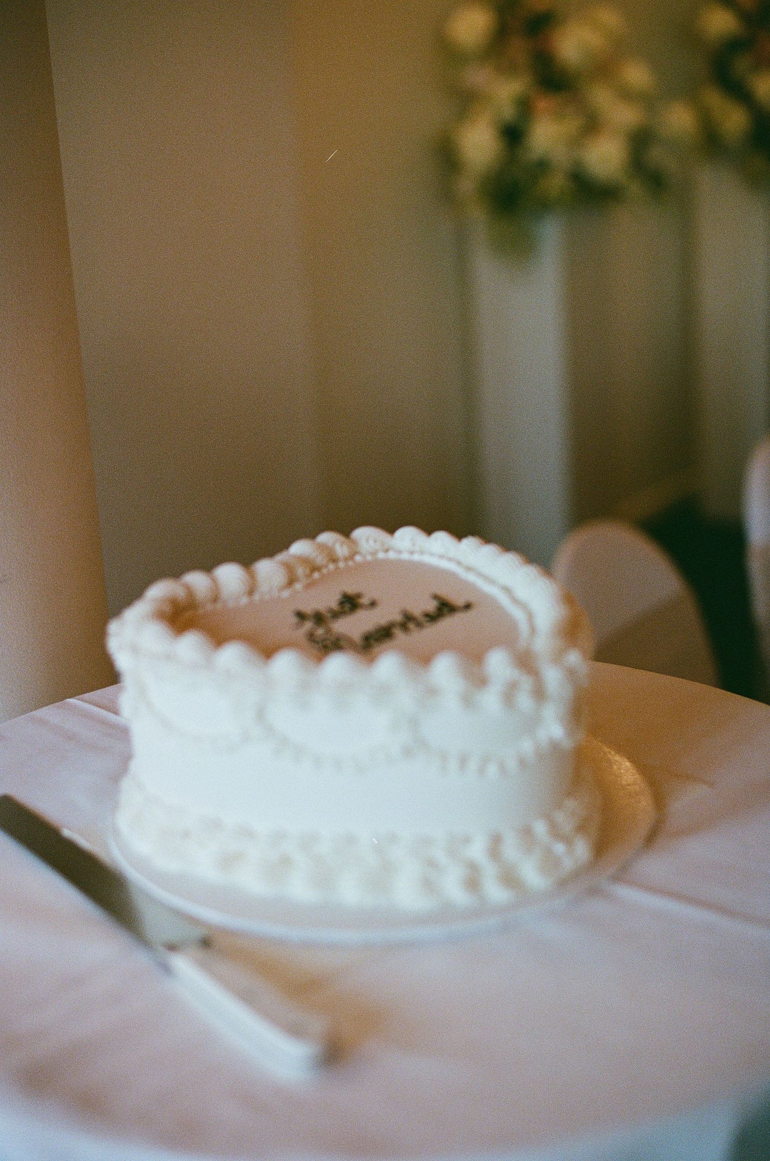 Elegant white wedding cake with Just Married inscription on a white tablecloth.