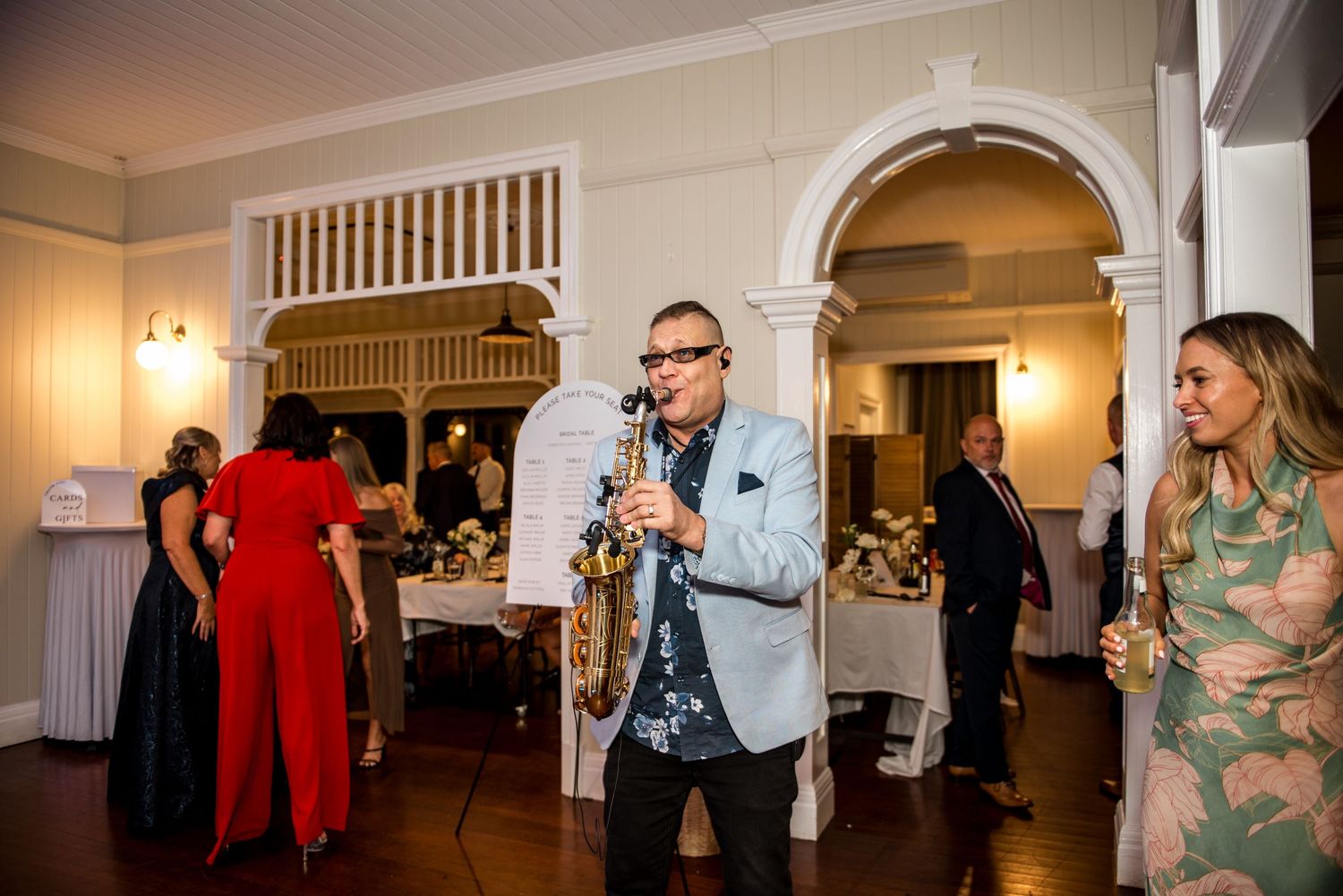 Saxophonist performing live music for guests at an elegant wedding reception venue.