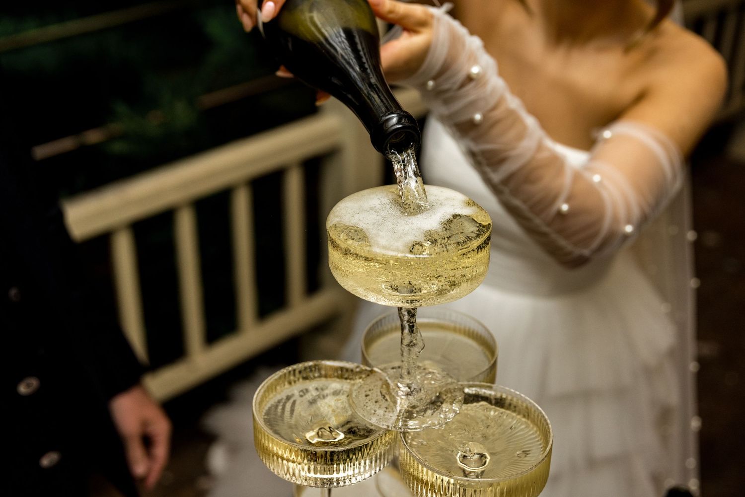Close-up of champagne cascading down a wedding champagne tower in coupe glasses.