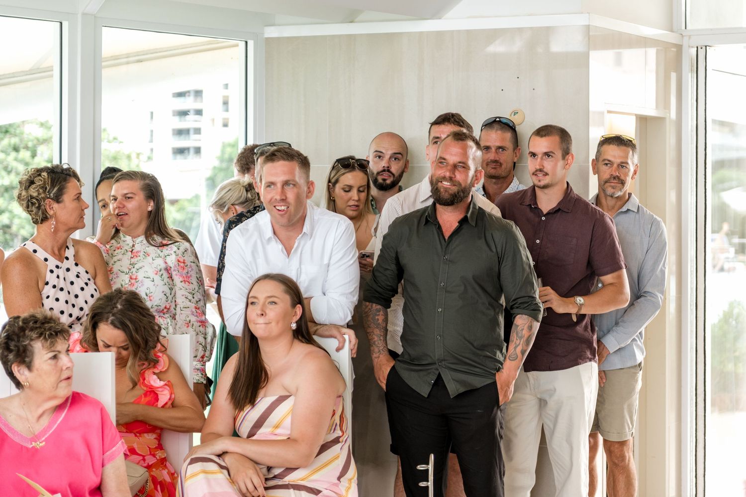 Wedding guests gathered inside a bright modern venue watching the ceremony.