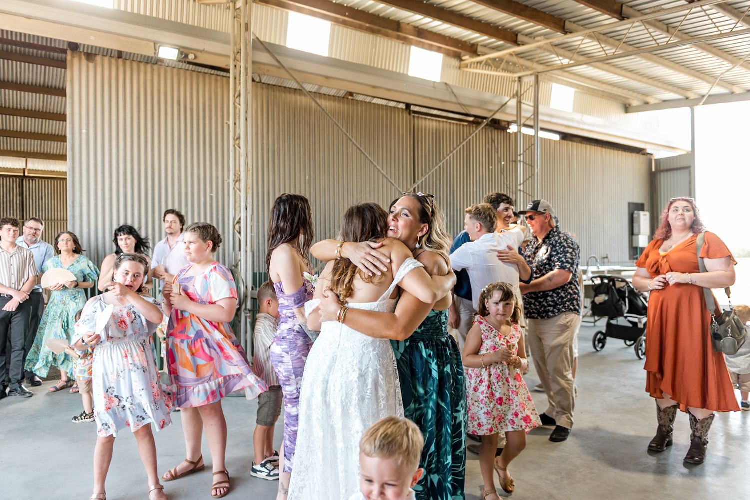 Wedding guests embrace and mingle during a relaxed rustic barn wedding reception.