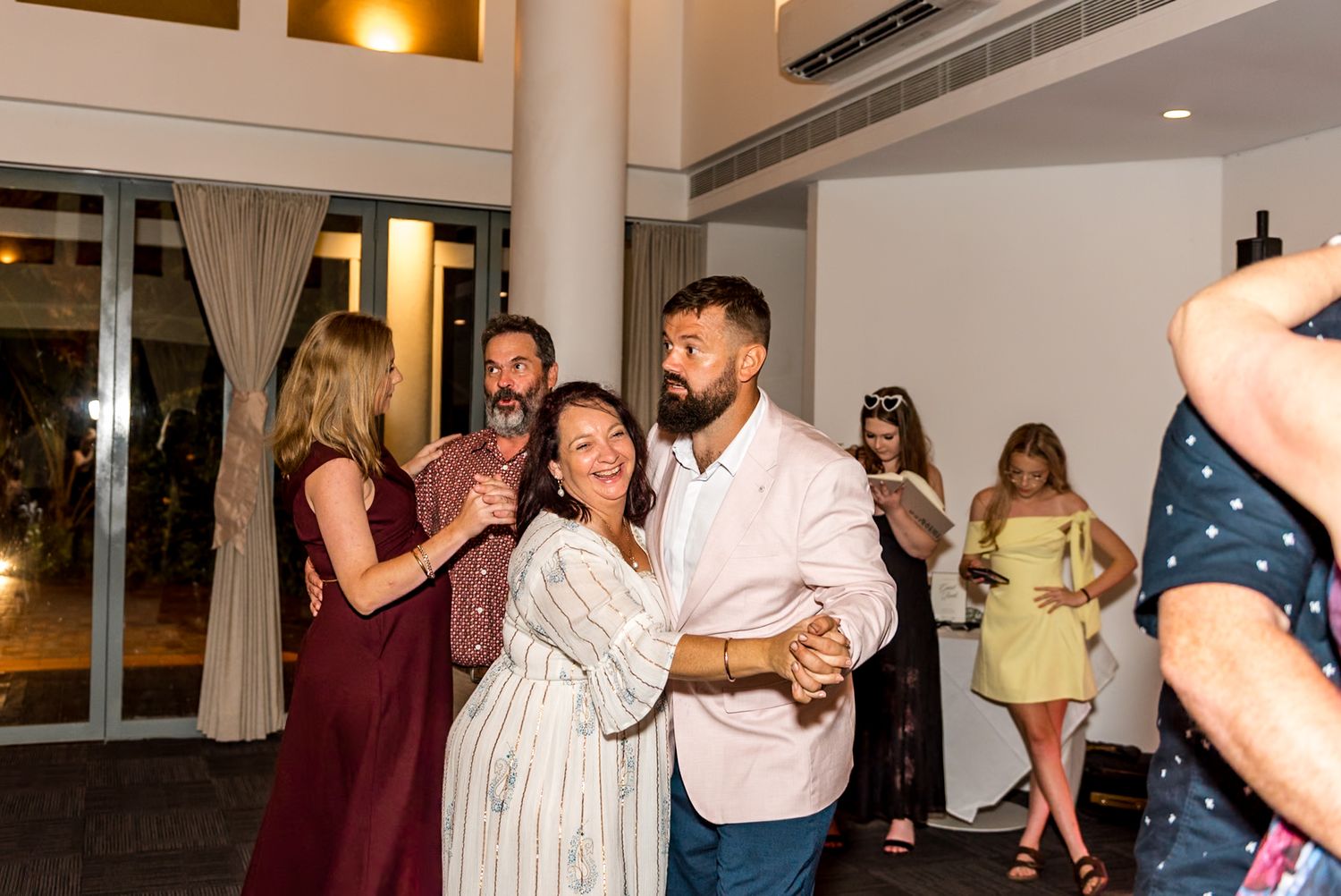 Couple shares a romantic dance at a wedding reception in a bright venue.