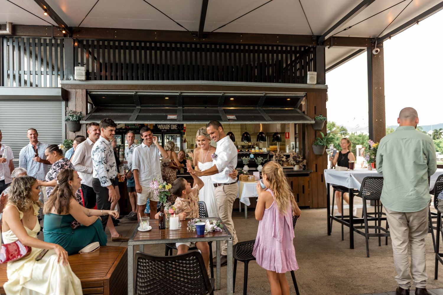 Wedding guests mingling and celebrating at an open-air tropical venue during a relaxed reception.