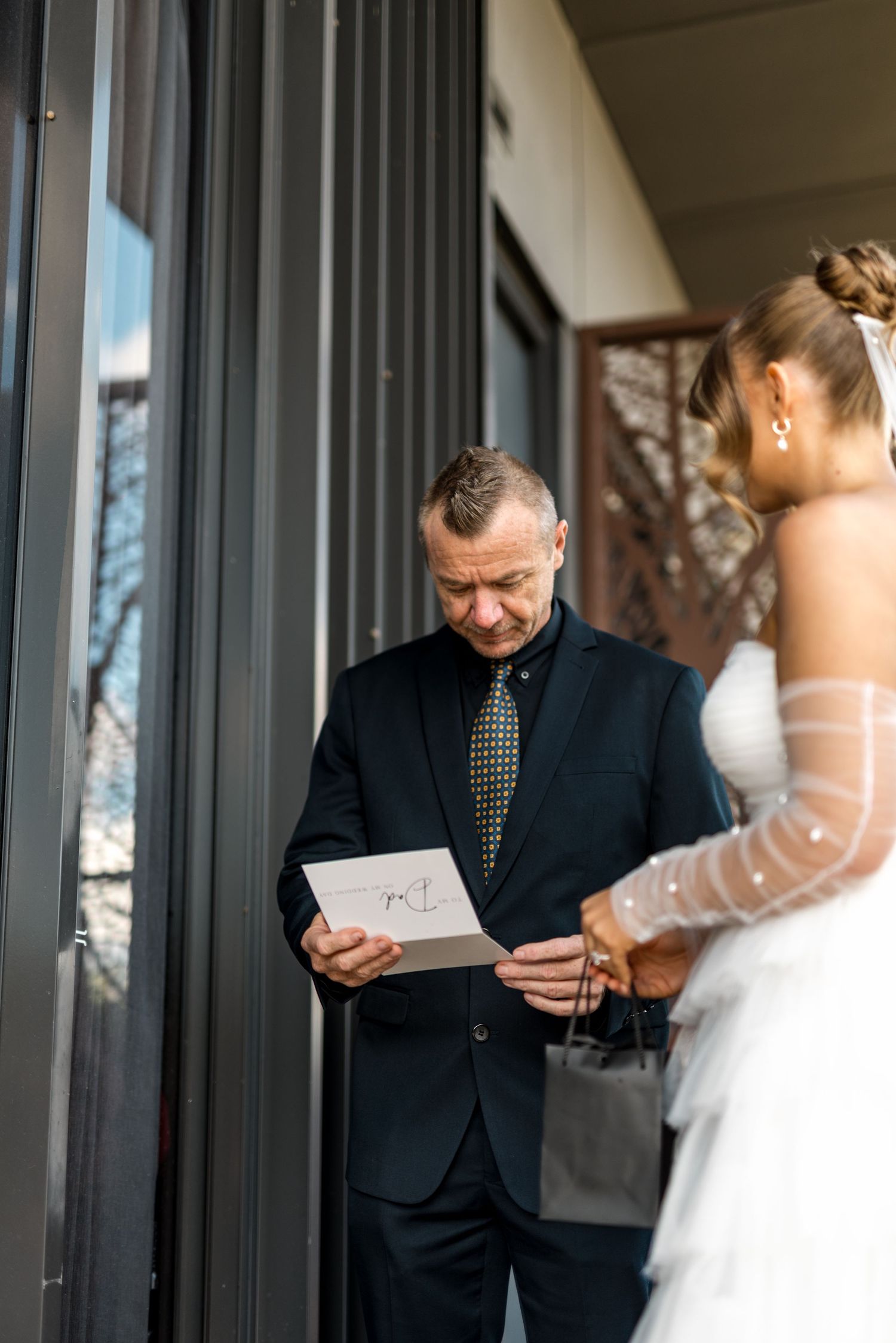 Father reads heartfelt letter from bride in white dress during touching pre-ceremony moment.