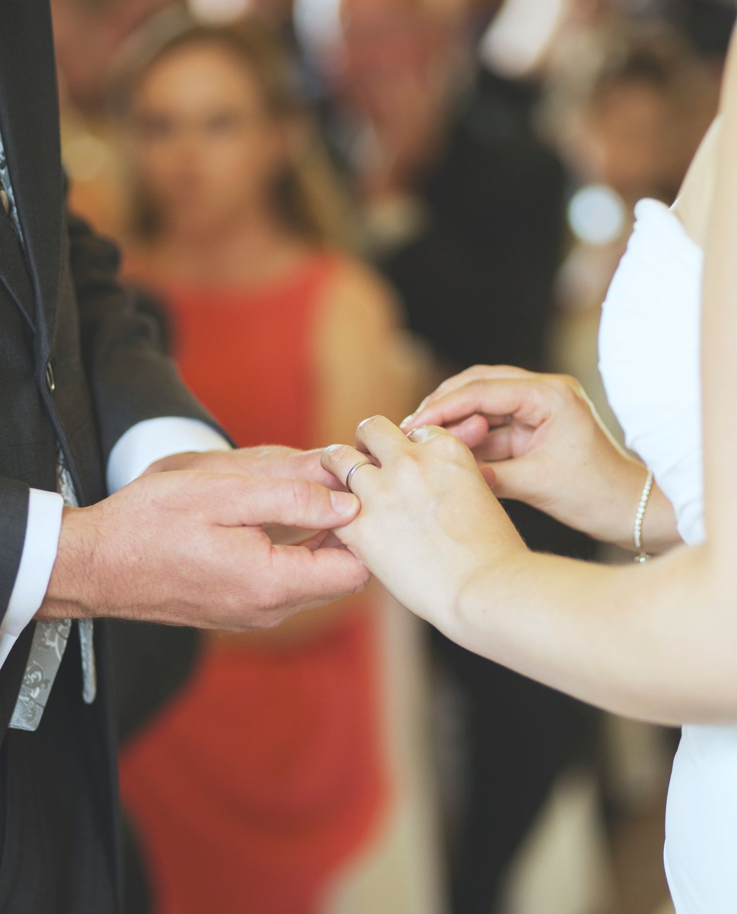 Close-up shot of a bride placing a wedding band on the groom's finger during the ring exchange ceremony.