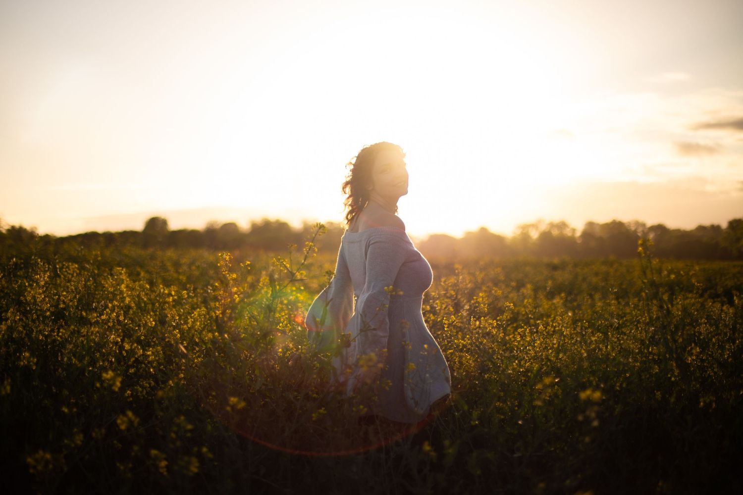 Shooting femme tours dans un champ au lever du soleil