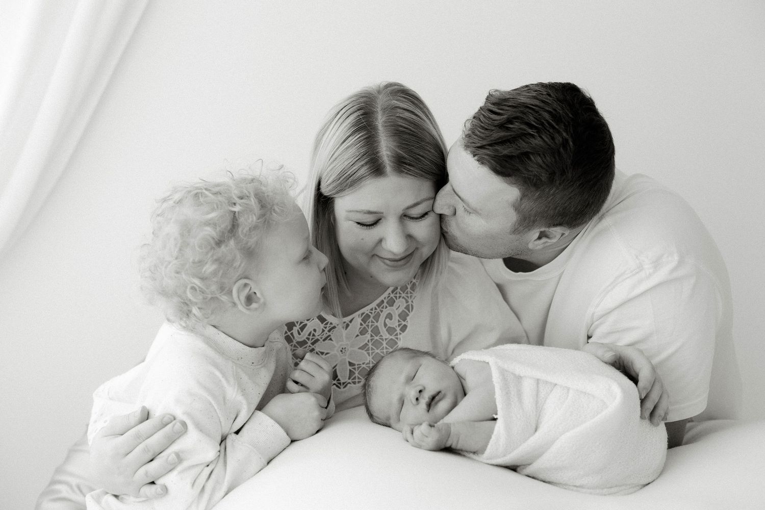 Koko perhe vastasyntyneen vauvan ympärillä studiossa newborn kuvauksessa