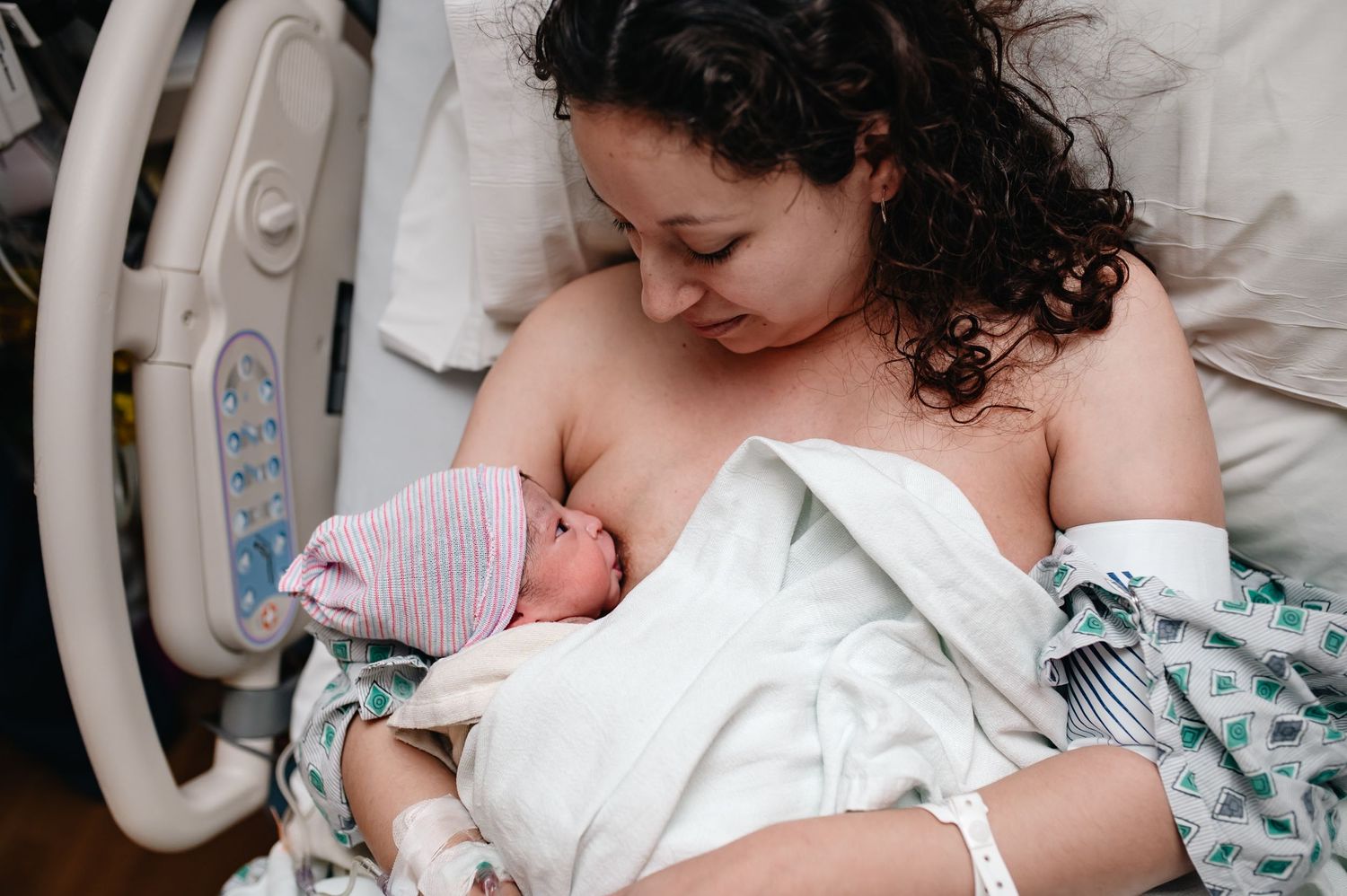 Benefits of breastfeeding, skin to skin and allowing physiological birth to happen. Newborn staring up at mom while breastfeeding