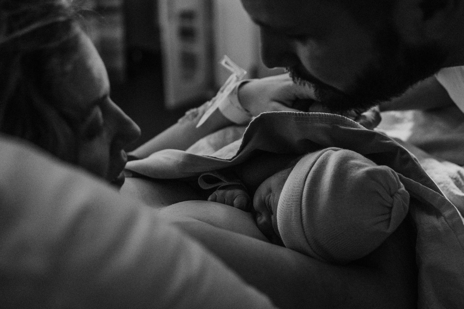 A black and white intimate photograph of a newborn baby being comforted in a nurturing hospital setting.
