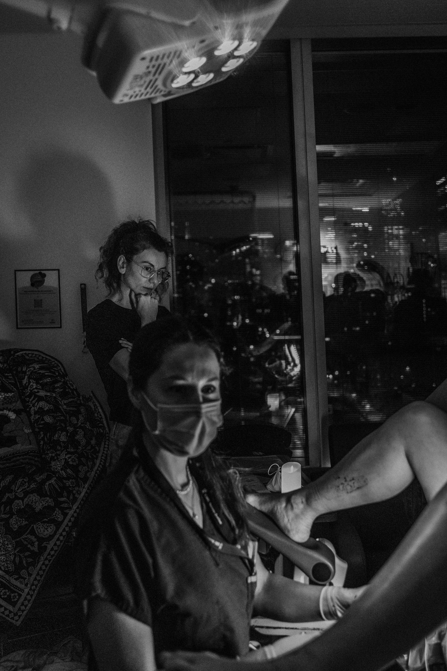 Medical staff work in a dimly lit room at night with city lights visible through a window in the background.
