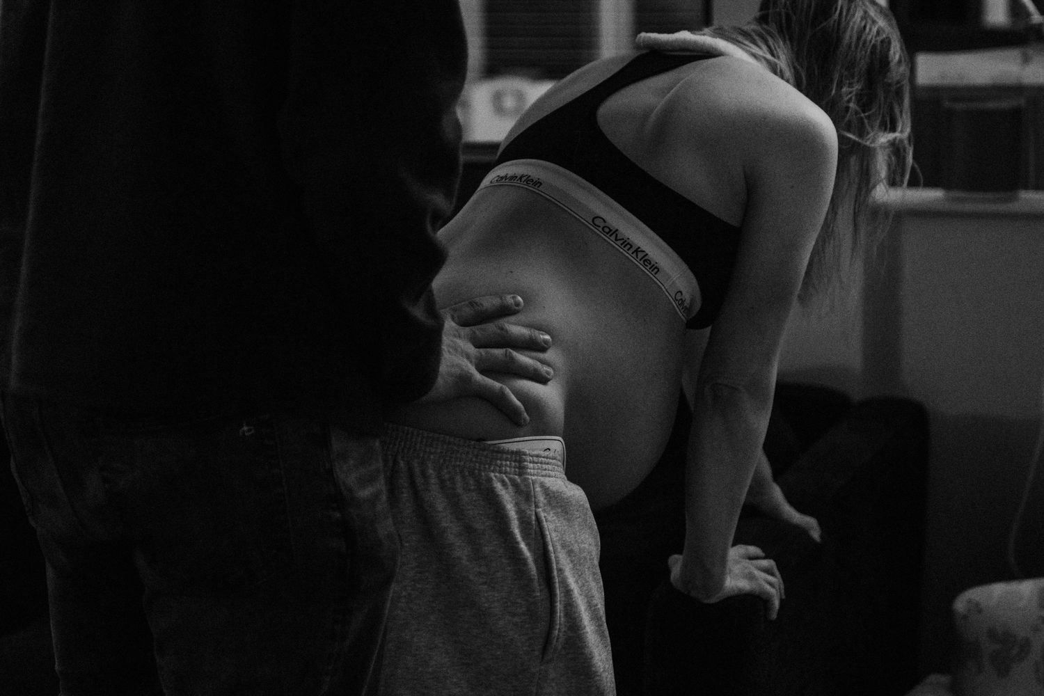 Black and white photo of a figure in sportswear leaning forward in a dimly lit interior space.