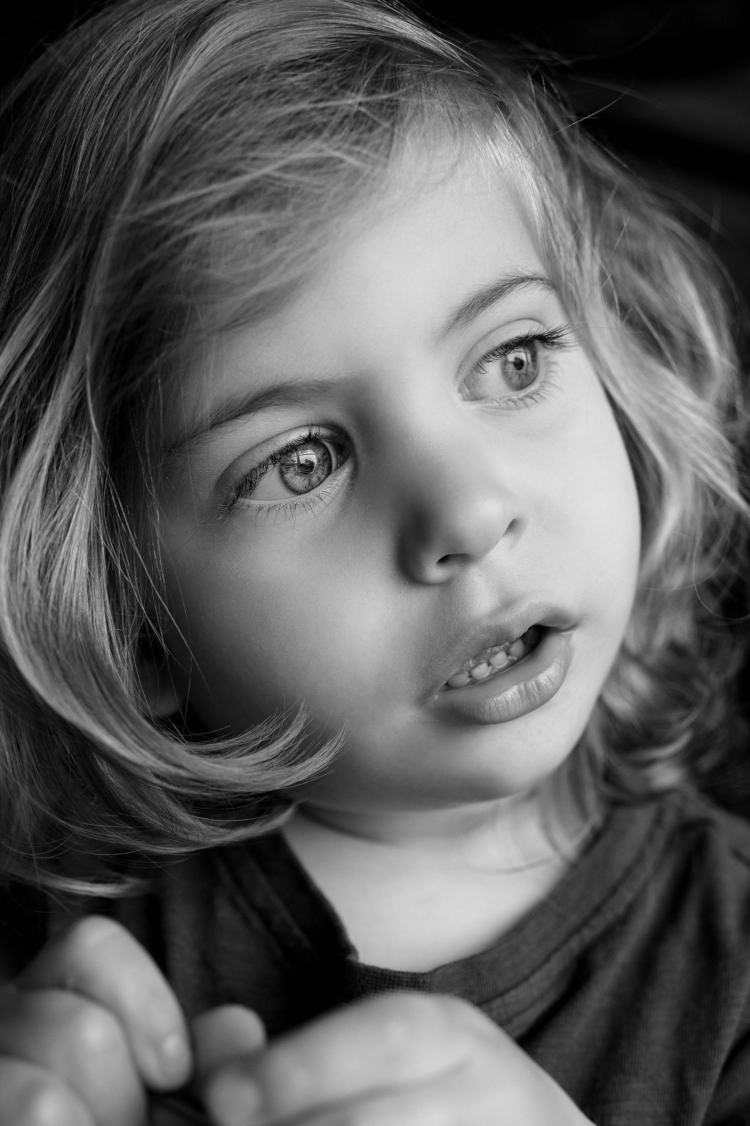 A striking black and white portrait showing wide-eyed expression and soft blonde curls.