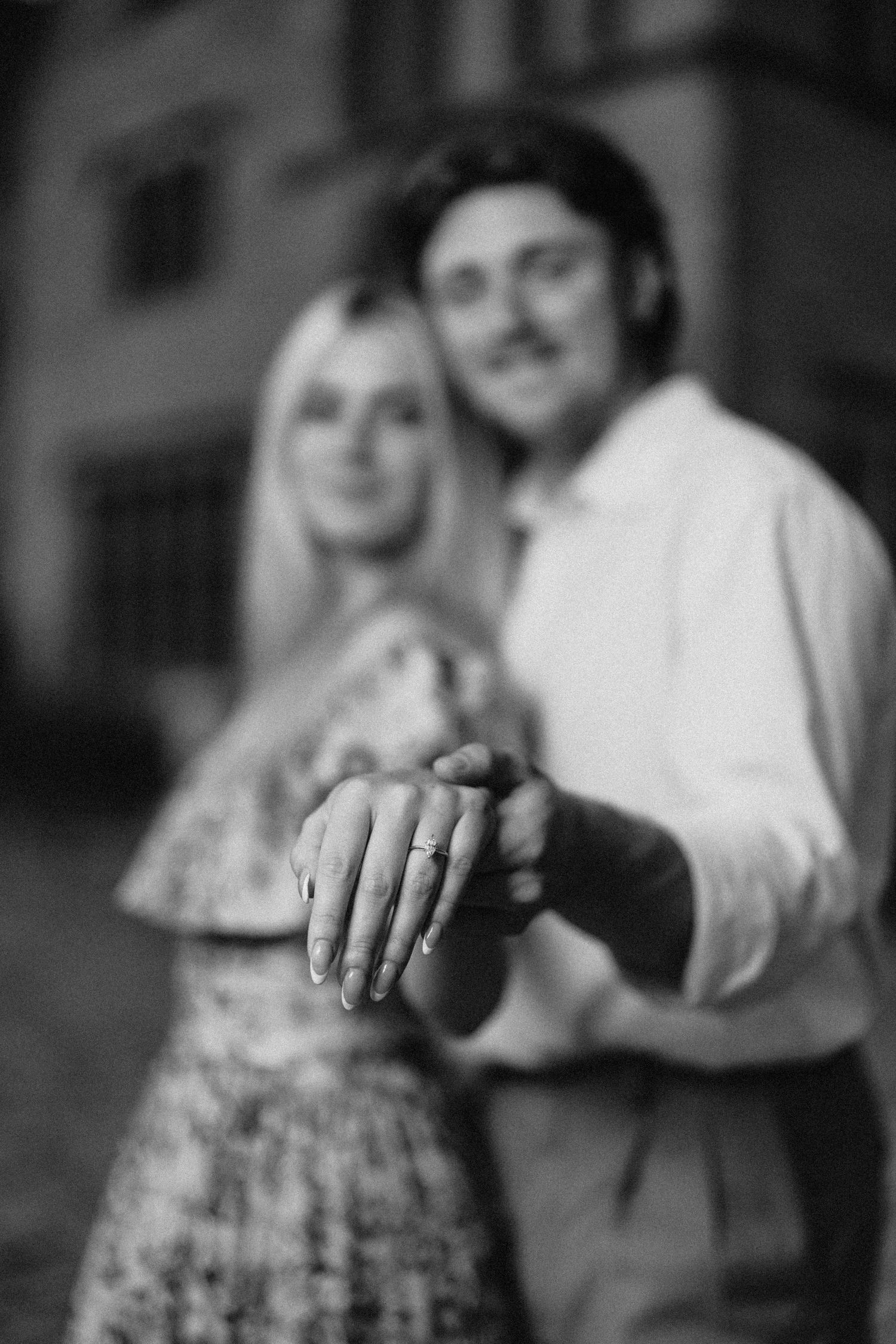 A black and white engagement photo highlighting a diamond ring on display.