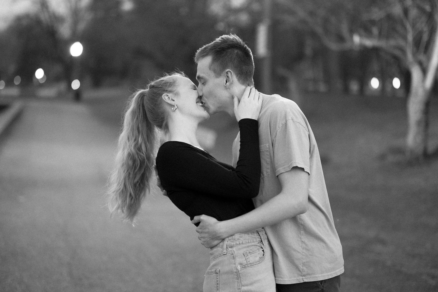 A black and white photo capturing an intimate embrace outdoors.
