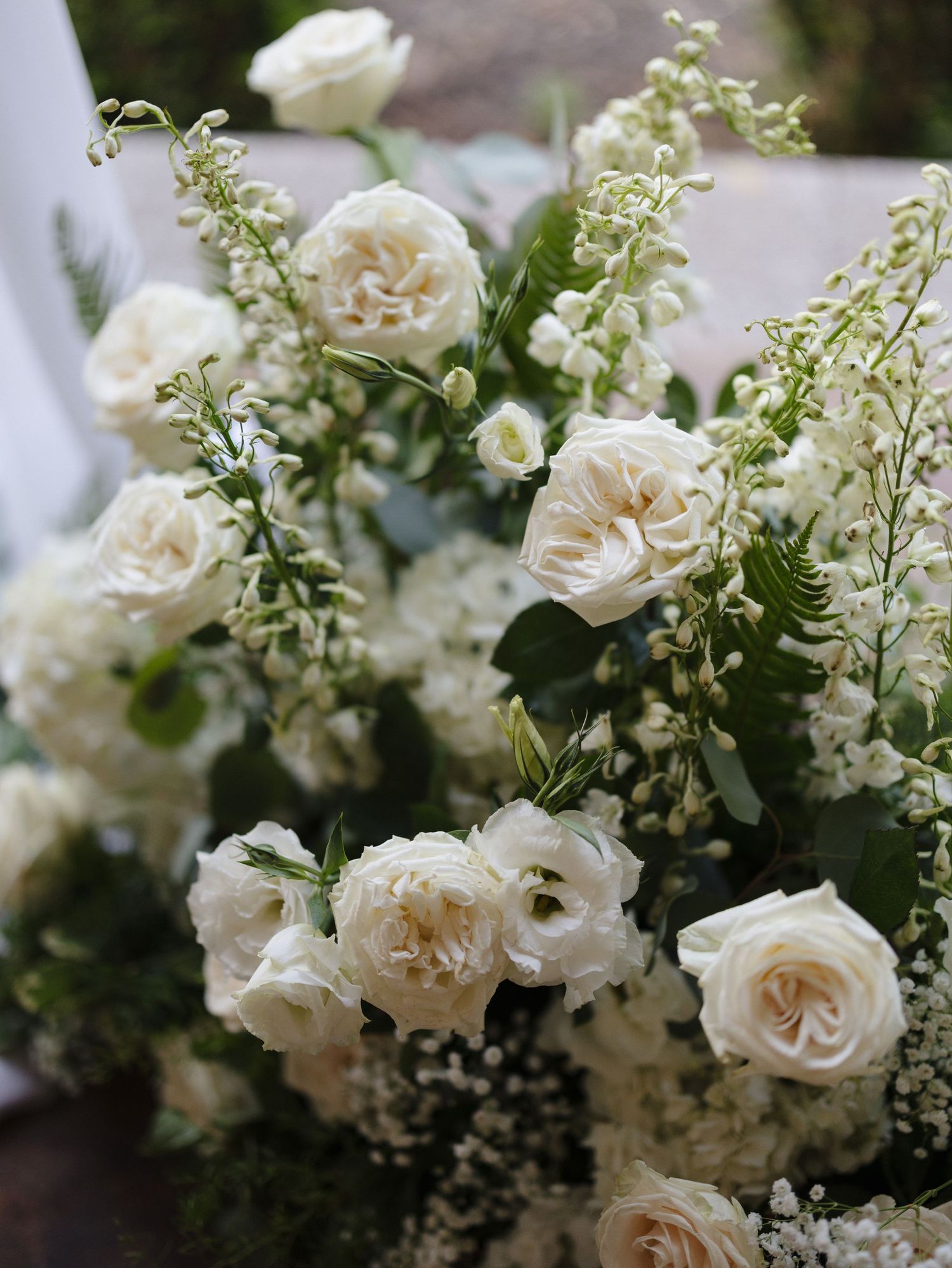 Elegant white garden roses and baby's breath floral arrangement with lush greenery, perfect for weddings.