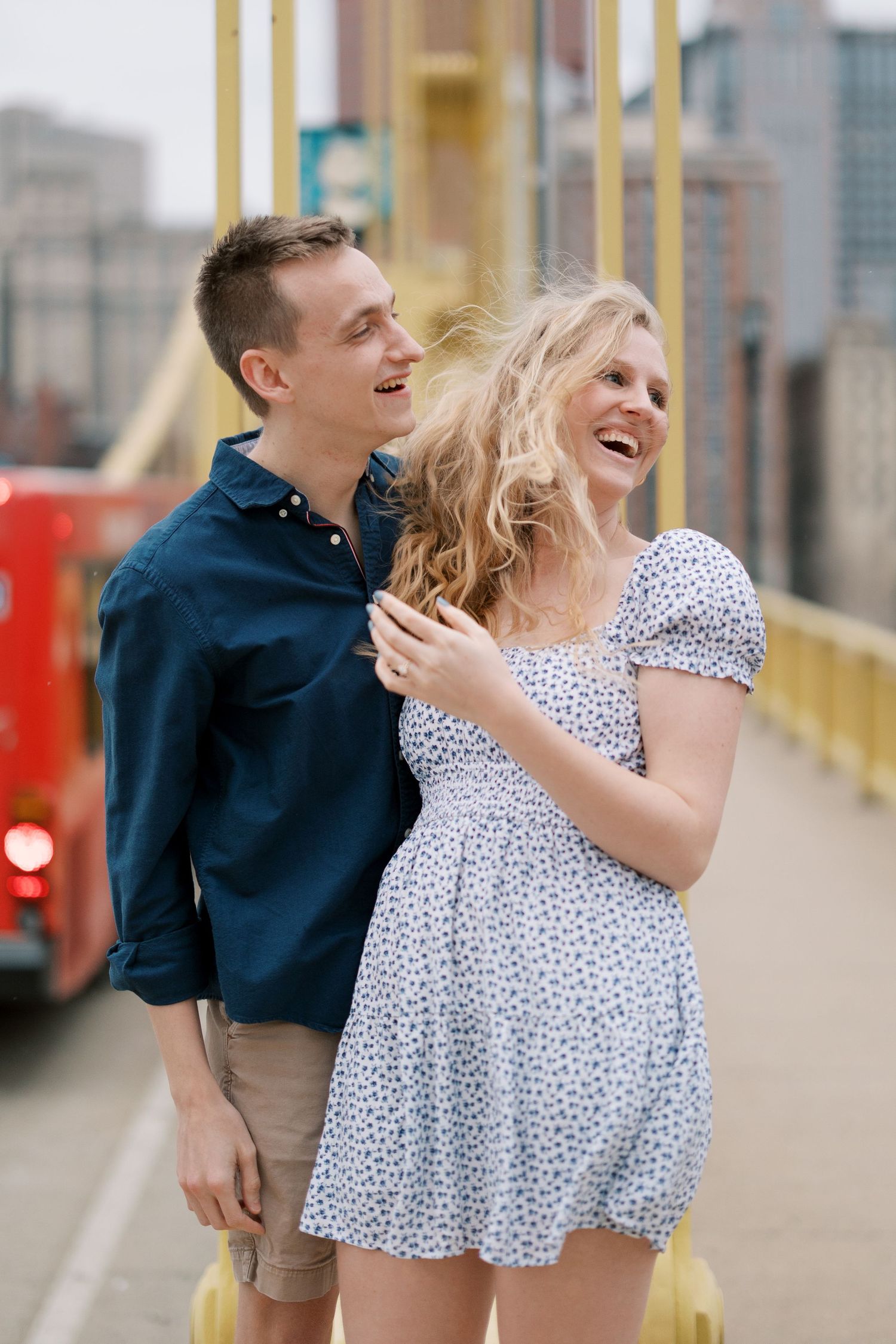 A joyful couple laughs together on a yellow bridge wearing coordinating navy and polka dot outfits.