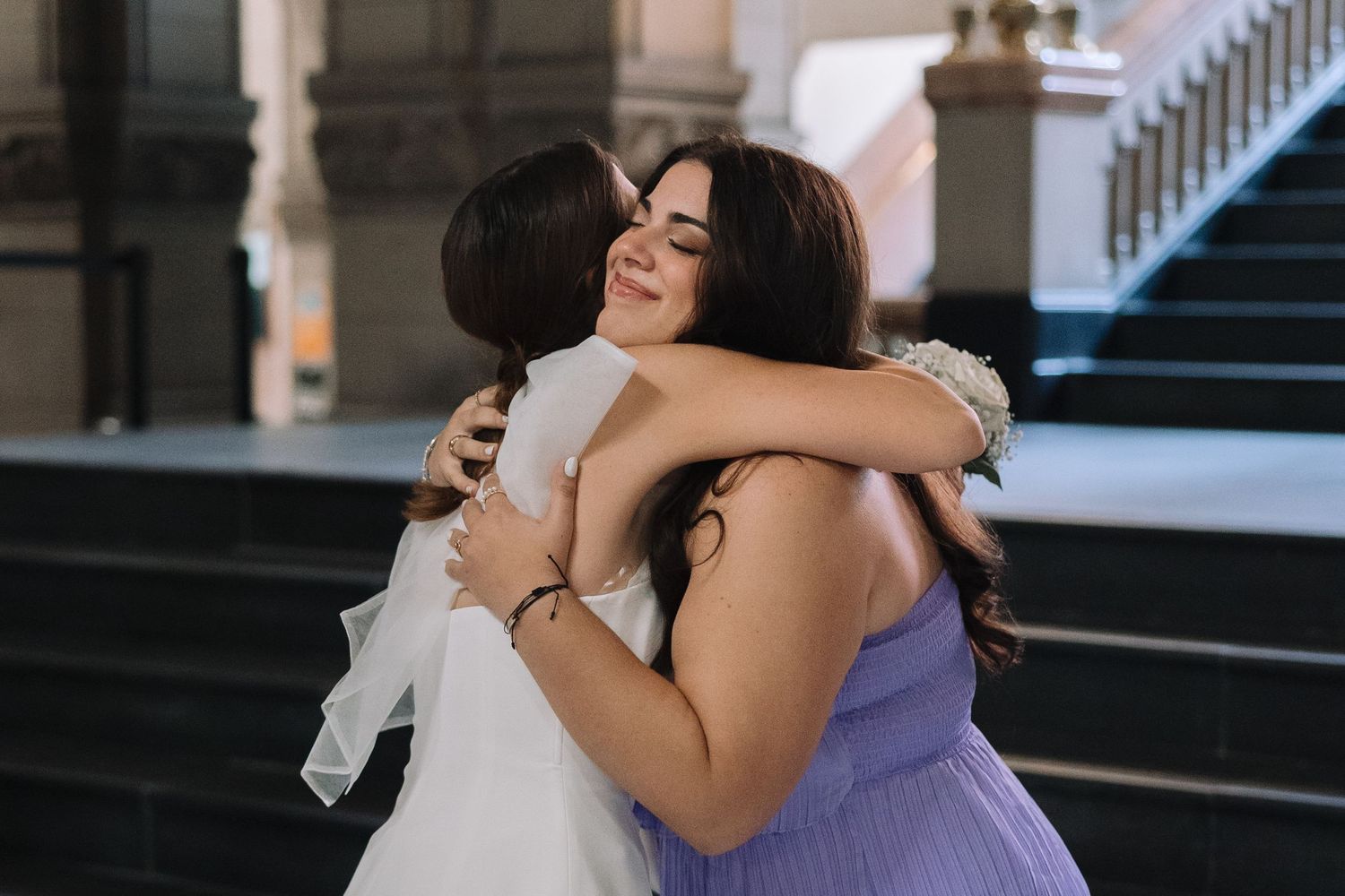 Emotional embrace between two in formal dresses during wedding celebration.
