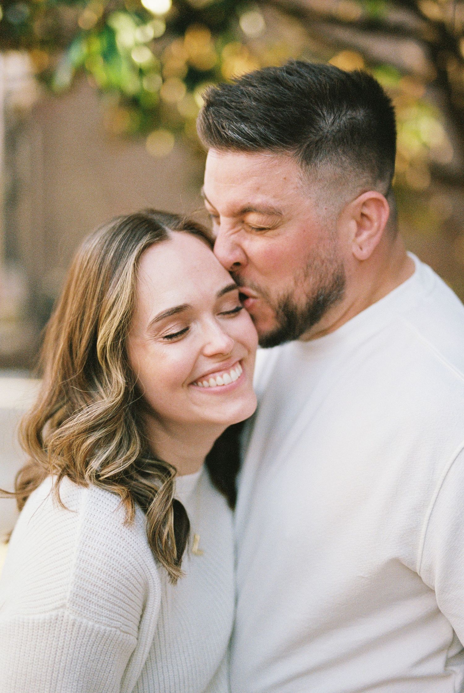 Four intimate shots of a couple in white sweaters sharing tender moments with soft lighting and bokeh background.
