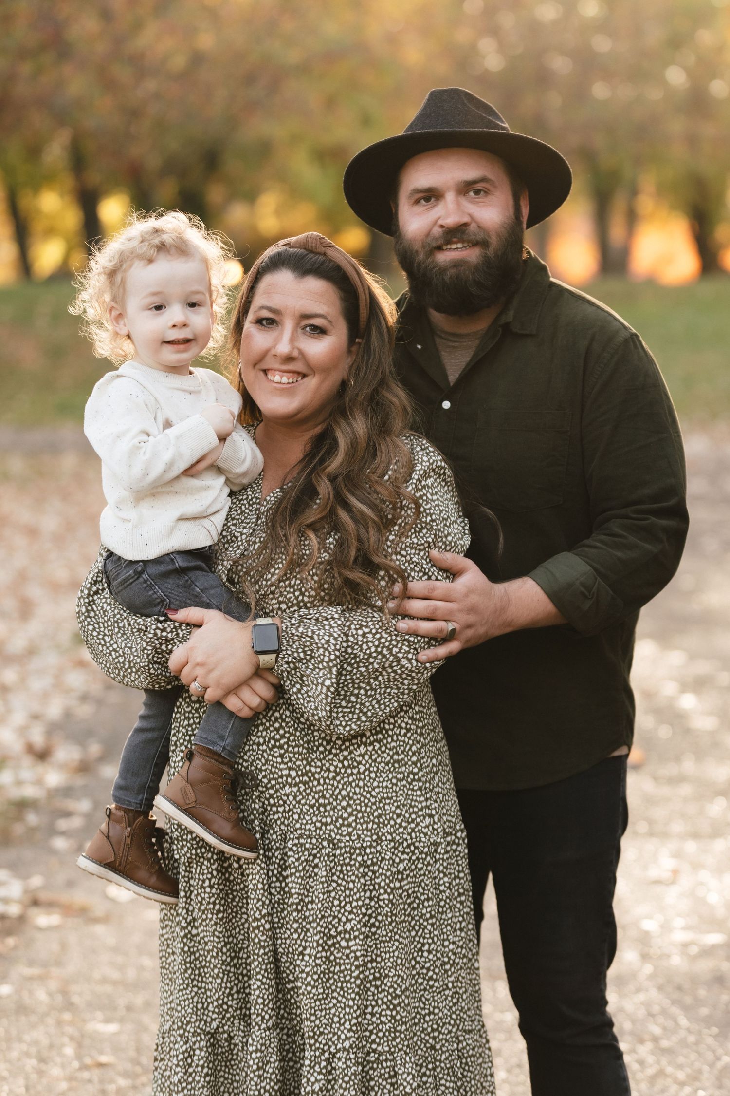 A family poses together outdoors during autumn wearing coordinated outfits in earth tones and leopard print.