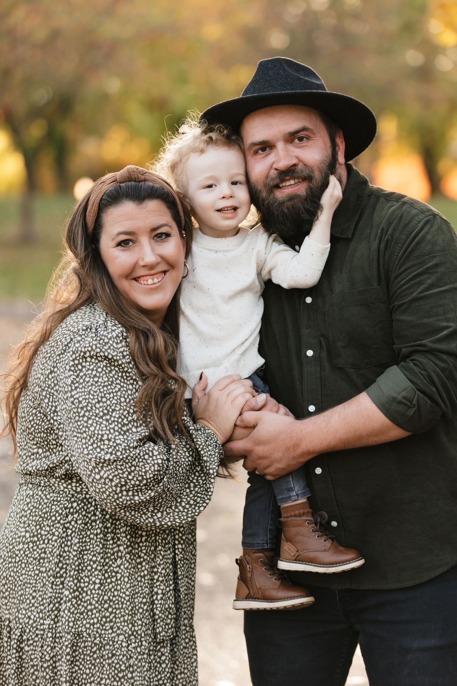 A family shares tender moments together in a fall outdoor photoshoot wearing coordinated casual outfits in earth tones.
